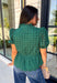 Elevate your fall wardrobe with this beautifully detailed hunter green top! Crafted from breathable cotton, this feminine top features intricate eyelet embroidery that adds timeless texture and charm. The ruffled accent neckline and flattering v-neck create an effortlessly polished look, while the button front and short puff sleeves with elastic cuffs offer both comfort and style. 