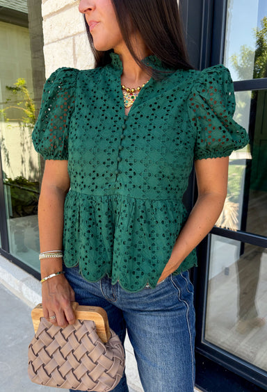 Elevate your fall wardrobe with this beautifully detailed hunter green top! Crafted from breathable cotton, this feminine top features intricate eyelet embroidery that adds timeless texture and charm. The ruffled accent neckline and flattering v-neck create an effortlessly polished look, while the button front and short puff sleeves with elastic cuffs offer both comfort and style. 