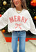 Bring the holiday spirit to life with this adorable “Merry” pullover by Main Strip! Designed in soft white fabric, this lightweight pullover features red and white gingham lettering with delicate white stitching for a festive finish. The matching gingham bow on the front adds the perfect touch of holiday charm. Cozy, comfy, and full of cheer—this pullover is made for everything from Christmas movie marathons to cookie baking days.
