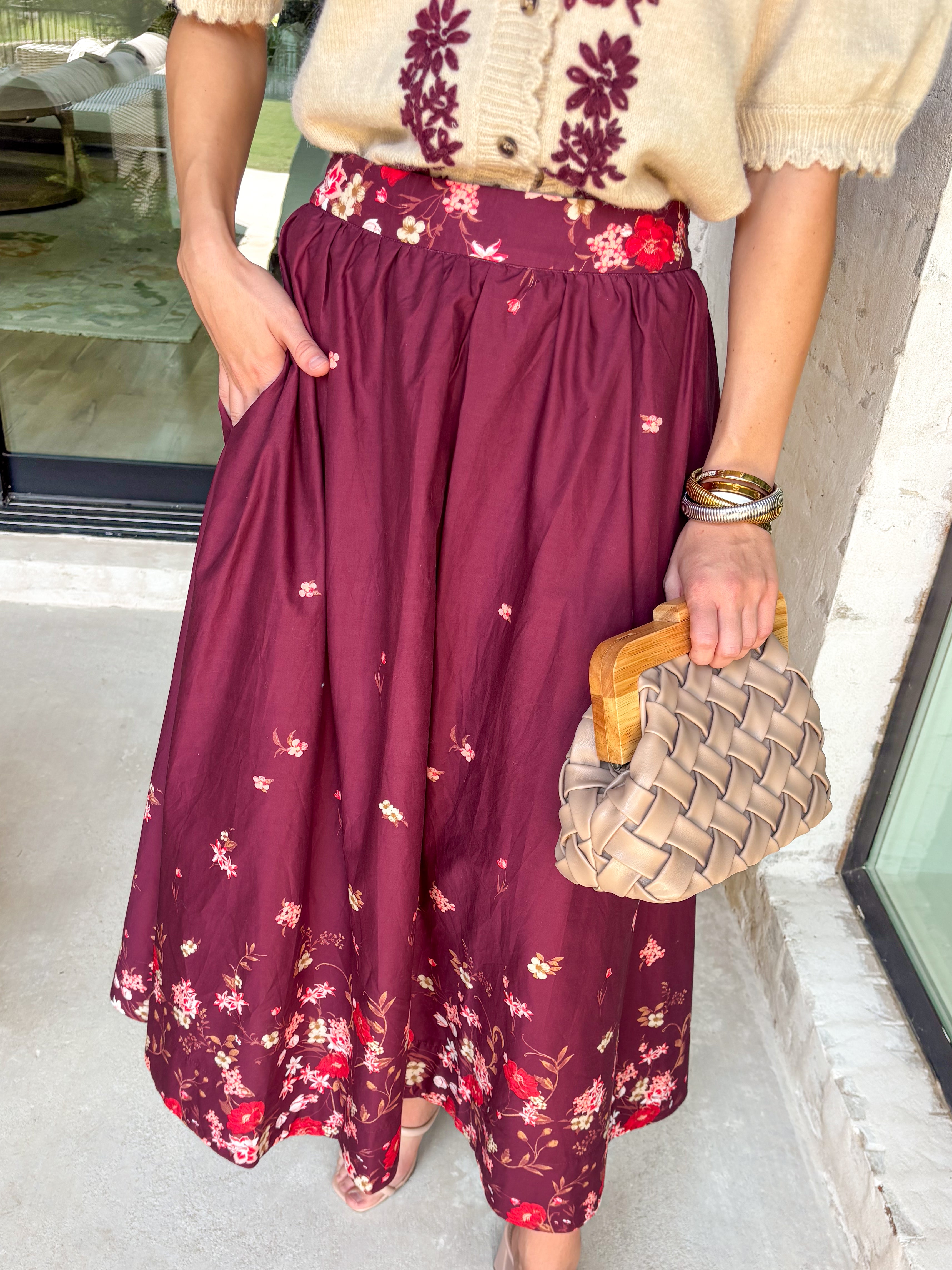 Feminine and flowy, this burgundy midi skirt is a seasonal standout. Designed with a floral border placement print, it adds just the right amount of charm while keeping the look timeless. The elasticated back waistband and side zipper closure make it comfortable and flattering, while side pockets add that everyday practicality we love. Fully lined in breathable cotton, this skirt is ready for everything from workdays to weekend strolls through the pumpkin patch.