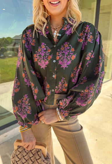 This dark green button-down top by Entro blends classic design with a seasonal twist. Featuring a lively orange and purple floral print, it adds just the right pop of color while keeping things effortless and chic. The breathable 100% cotton fabric makes it comfortable enough for everyday wear, and the button-front style gives you plenty of ways to layer and style it through the season. Perfect for bringing a touch of fall flair to your wardrobe.