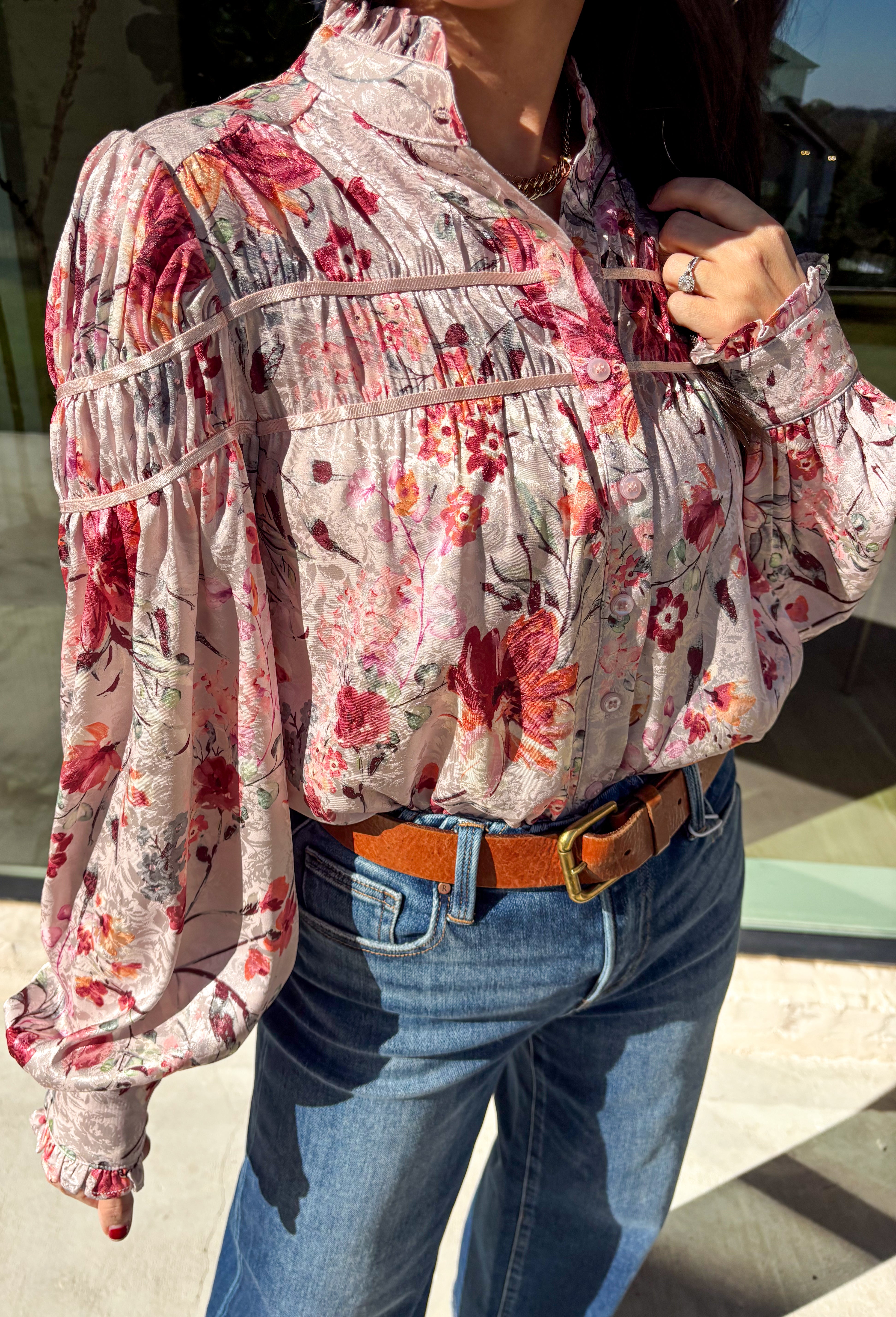 Bring a touch of winter romance to your wardrobe with this mauve floral button-down top by Fate. Featuring shades of pink, burgundy, gray, and orange, the floral print adds a warm pop of color against the chilly season. The ruffled neckline and cuffs give it a soft, feminine finish—perfect for dressing up denim or layering under a structured jacket all winter long.