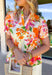 This white babydoll top is giving all the fresh spring energy with its colorful floral print in shades of orange, pink, and green. The relaxed babydoll silhouette flows beautifully, creating that easy, throw-on-and-go fit we all love when the weather starts warming up. It’s light, airy, and made for sunshine-filled days. The flattering v-neckline keeps it feminine and easy to style, while the smocking on the back of the sleeves adds subtle texture and a comfortable fit. 