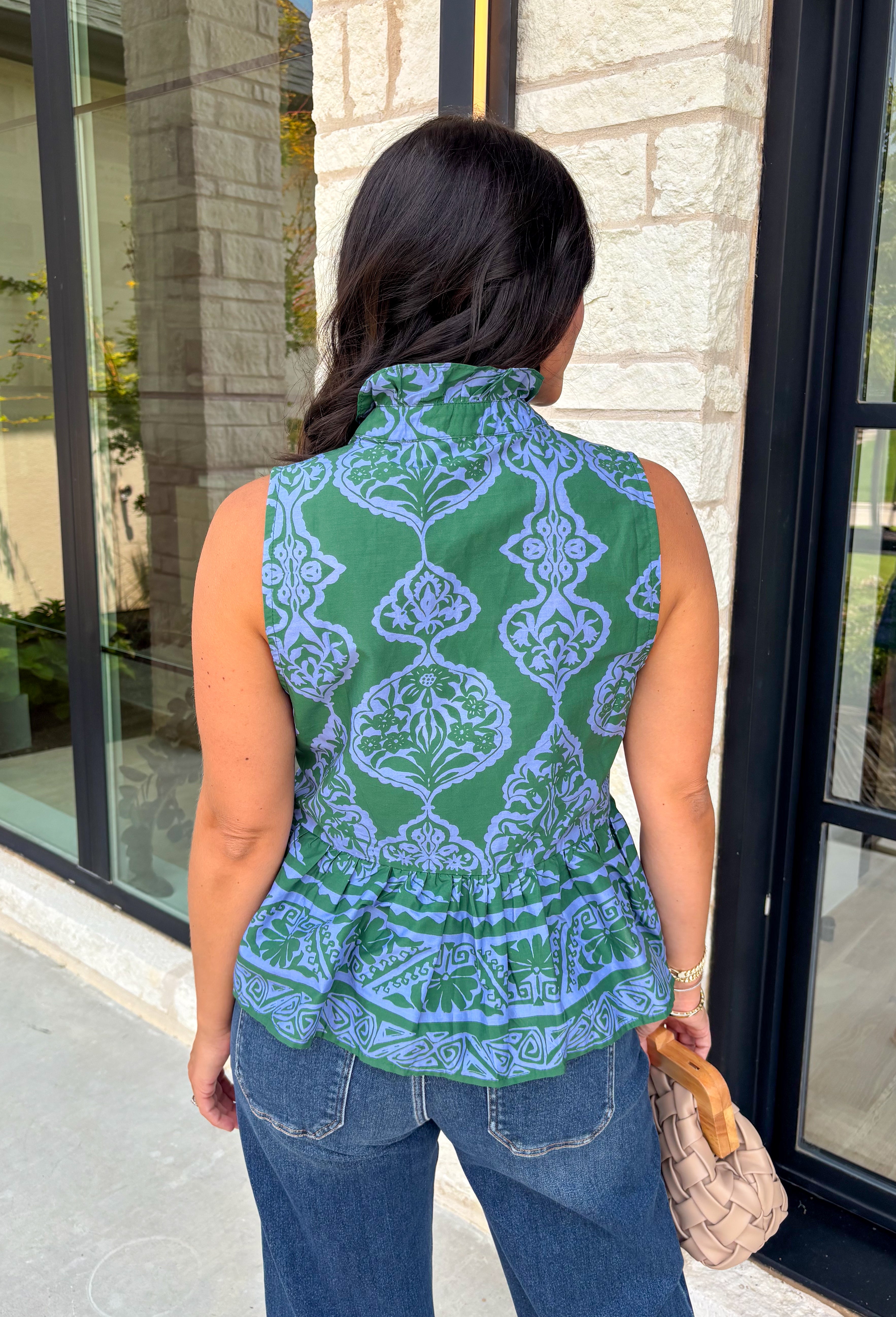 Bring a fresh pop of color to your fall wardrobe with this effortlessly charming paisley top. Featuring a beautiful green backdrop with a light blue paisley print, this sleeveless blouse is equal parts classic and feminine. The ruffled neckline and button-front details add a polished touch, while the peplum hem creates a flattering silhouette that's easy to wear from workdays to weekends. 