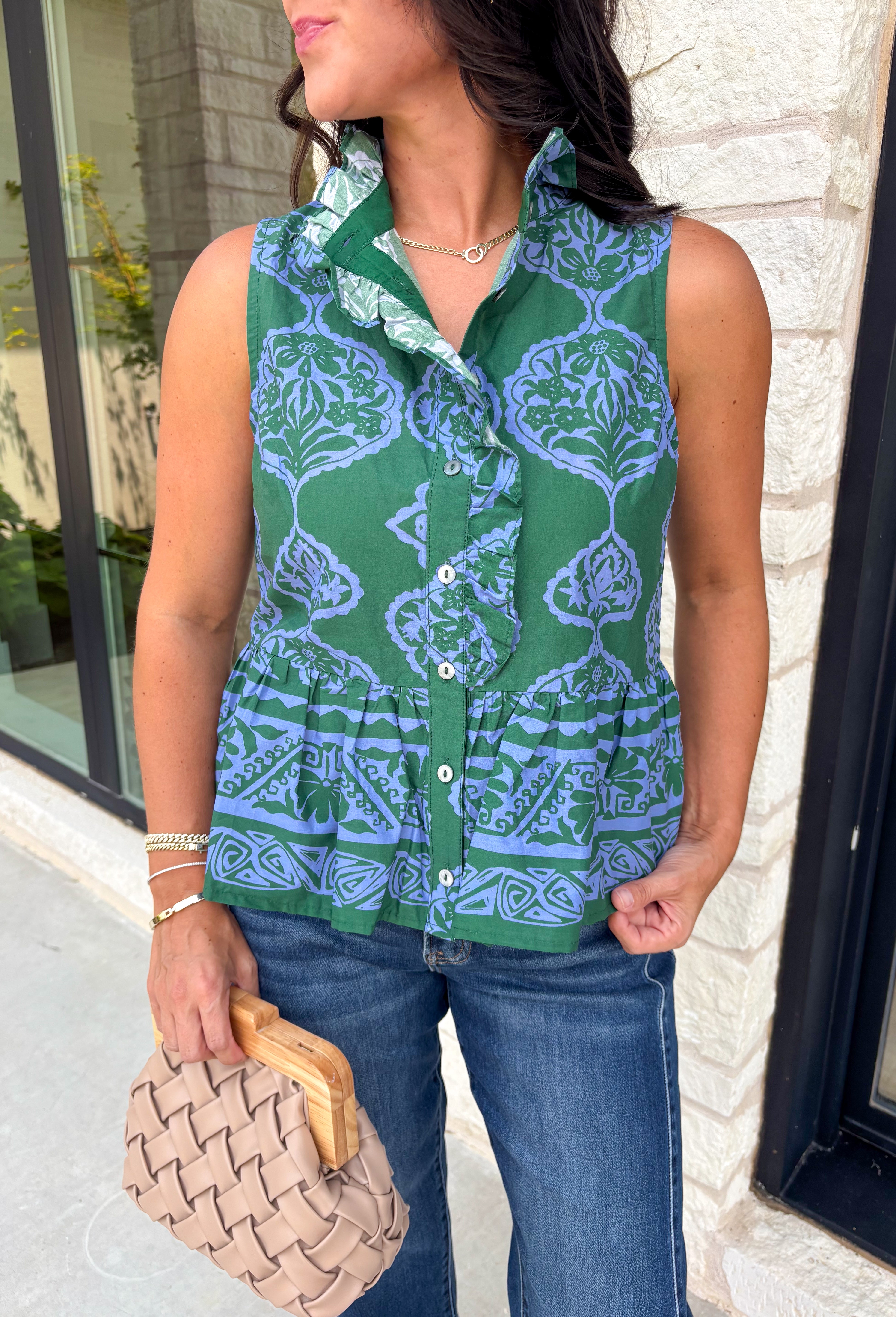 Bring a fresh pop of color to your fall wardrobe with this effortlessly charming paisley top. Featuring a beautiful green backdrop with a light blue paisley print, this sleeveless blouse is equal parts classic and feminine. The ruffled neckline and button-front details add a polished touch, while the peplum hem creates a flattering silhouette that's easy to wear from workdays to weekends. 