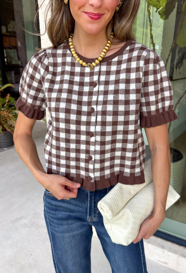 Sweet, timeless, and full of charm, this gingham cardigan is the perfect layer for the season! Featuring a classic brown and white gingham pattern, this button-down knit is finished with darling ruffle details on the sleeves and hem for an extra feminine touch. The soft, cozy knit makes it easy to wear on its own or layered over your favorite basics, creating an effortlessly polished look you'll love from weekday outings to weekend brunch.