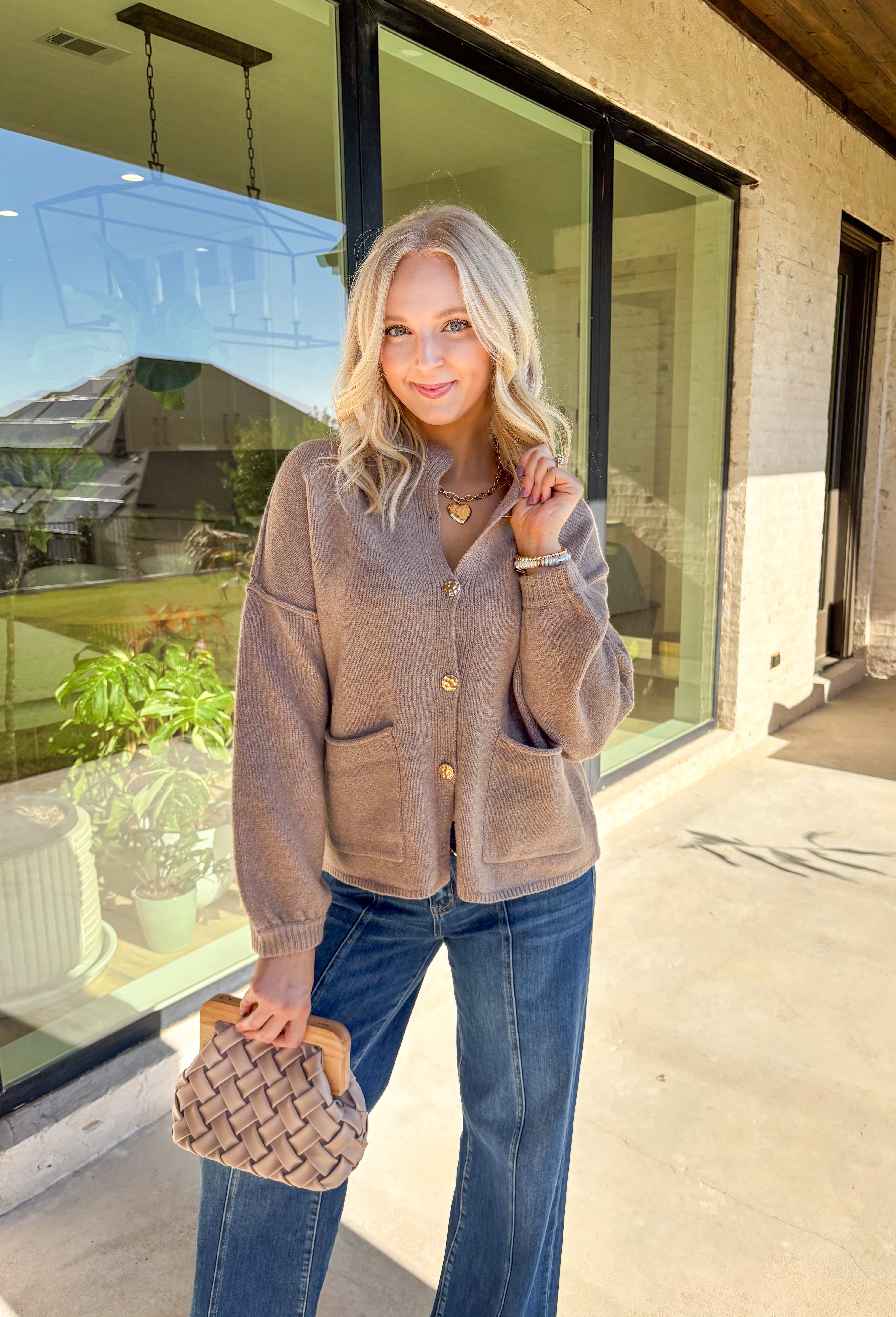 Warm, polished, and easy to wear—this brown knit cardigan is the perfect cozy layer for fall. The mock neck keeps the look refined, while hammered gold-tone buttons add a touch of shine to the button-front closure. Front pockets make it as practical as it is stylish, and the soft knit blend with a hint of wool offers just the right amount of warmth for crisp days. Whether layered over a dress or paired with jeans, it’s a seasonal staple you’ll reach for again and again.