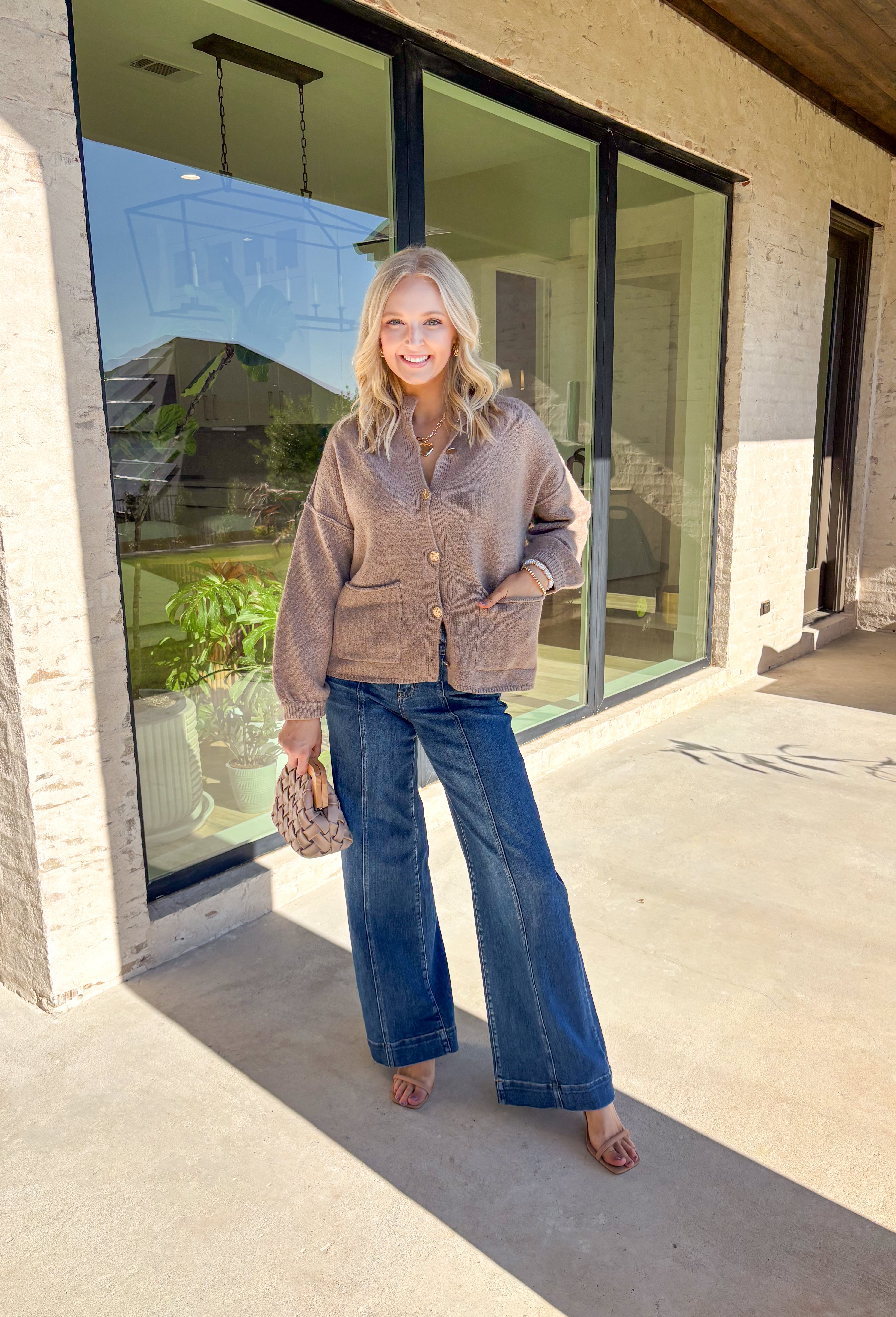 Warm, polished, and easy to wear—this brown knit cardigan is the perfect cozy layer for fall. The mock neck keeps the look refined, while hammered gold-tone buttons add a touch of shine to the button-front closure. Front pockets make it as practical as it is stylish, and the soft knit blend with a hint of wool offers just the right amount of warmth for crisp days. Whether layered over a dress or paired with jeans, it’s a seasonal staple you’ll reach for again and again.
