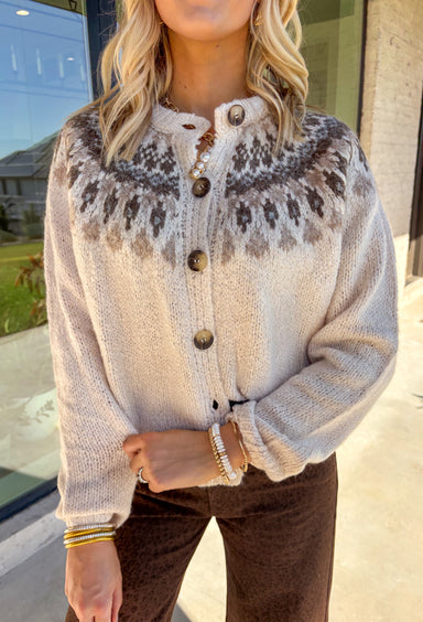 Add a pop of cozy charm to your wardrobe with this chunky knit button-down cardigan by Blu Pepper. Featuring a round neckline and long sleeves, it’s designed with a vibrant Fair Isle pattern in neutral tones—making it an easy piece to mix and match with your seasonal staples. Finished with a button-front closure, it’s just as easy to wear open as it is closed, giving you endless layering possibilities. Warm yet breathable, this cardigan is perfect for styling through the season.