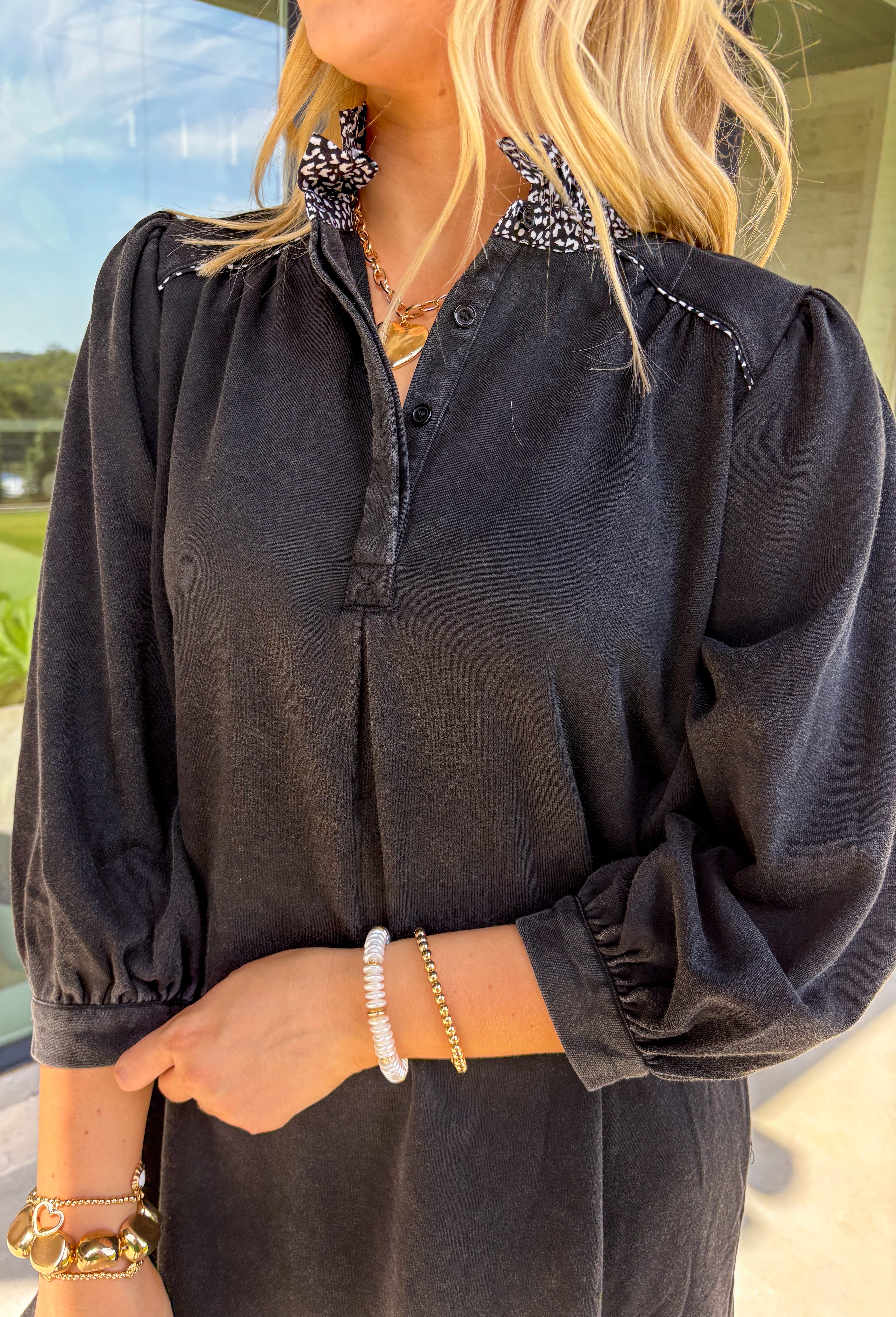 Classic black gets a playful twist in this long sleeve dress featuring subtle leopard details. The black and white leopard print peeks out along the ruffle-trimmed neckline and hem, adding just the right amount of contrast. With its relaxed fit and comfortable cotton blend, this dress is easy to wear from day to night—perfect for adding a little personality to your wardrobe.