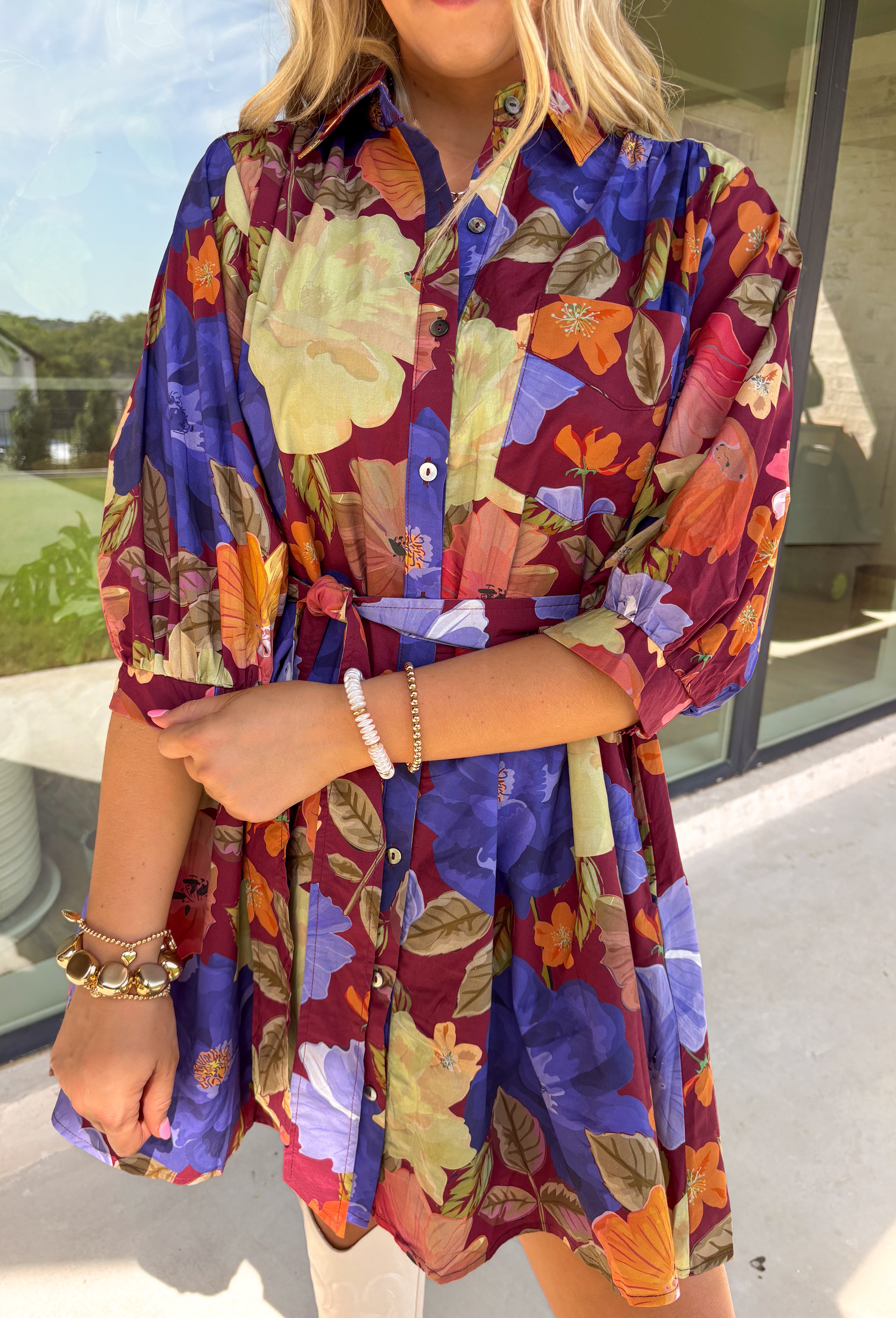 A fall favorite with effortless charm, this burgundy mini dress is blooming with autumn-inspired florals. The puff sleeves give it a feminine touch, while a front chest pocket and self-tie waist add both function and shape. Designed with a button-front closure, side pockets, and a fully lined interior, this dress is as practical as it is pretty. Made in breathable cotton, it’s an easy piece to style for everything from casual days to seasonal gatherings.