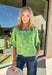 Fresh, fun, and full of texture, this green short sleeve top by Voy is an easy spring standout. Designed with a monochromatic textured floral print, it adds dimension and detail while keeping the look clean and wearable. Royal blue embroidered trim along the front, cuffs, and hem gives it a bold pop of contrast, and the square neckline adds a flattering, modern finish. Lightweight and easy to style, this top is perfect for brightening up your everyday spring outfits.