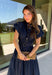 There’s something about a great denim dress that makes getting dressed feel instantly easier. This dark wash midi dress from Entro features a stand collar and partial gold button front that adds a polished touch to the classic denim look. Cap sleeves keep the silhouette easy to layer as the seasons change, while the coordinating self-tie belt lets you add definition at the waist. Finished with convenient side pockets, this versatile dress can take you from casual office days and lunch plans to football week