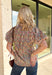 Bring a fresh take on fall florals to your wardrobe with this beautifully detailed top from Entro. Designed with a soft light blue backdrop and a floral print in rich autumn shades, this feminine blouse is full of charming details. Blue and olive contrast trim along the front adds a unique pop of color, while the subtle ruffle neckline and puff sleeves create a timeless, polished silhouette. Crafted from breathable cotton, this versatile top is perfect for everything from workdays to weekend brunches.