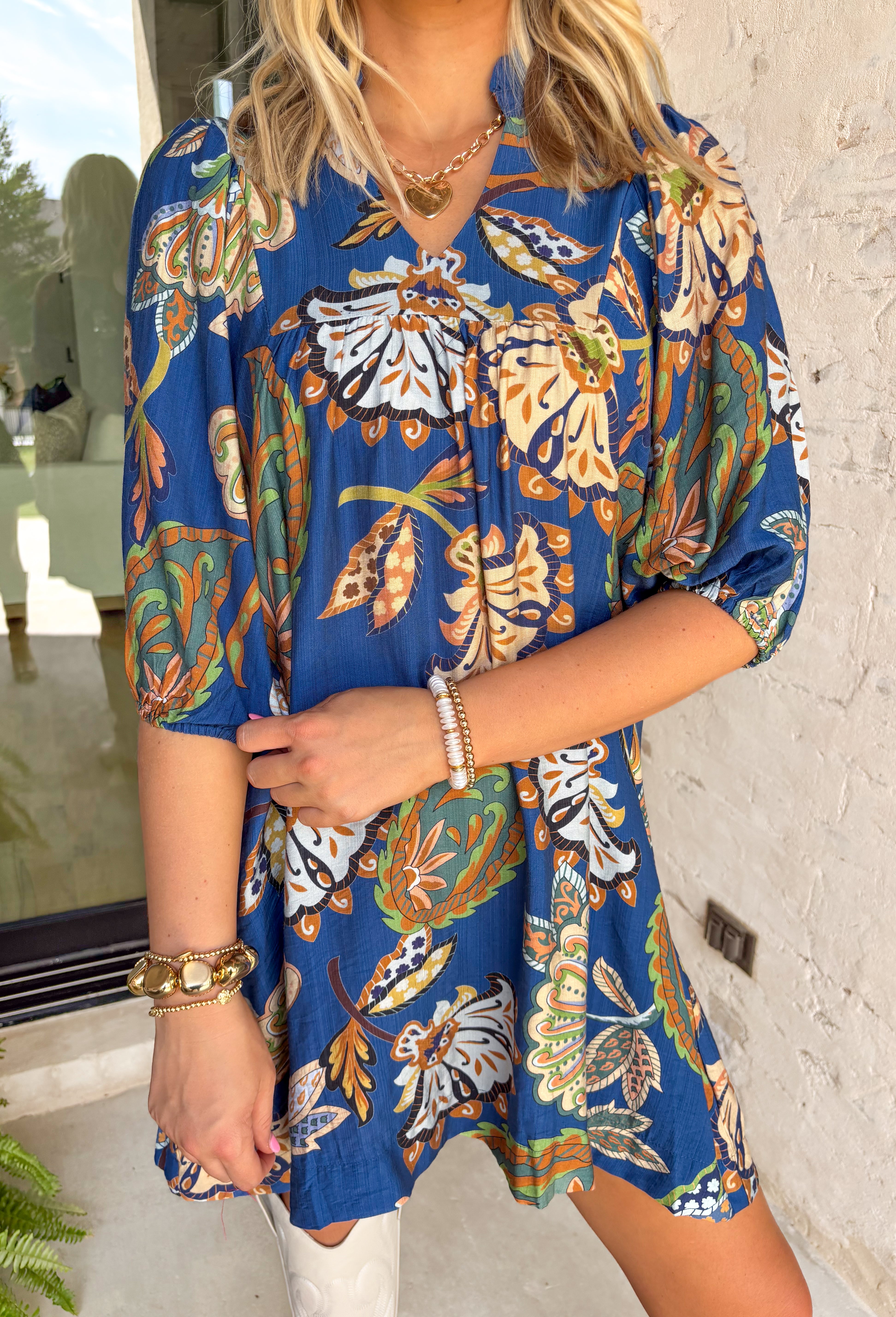 Add a touch of whimsy to your fall wardrobe with this navy long sleeve dress. Featuring an abstract floral and paisley print in soft tones of light blue, tan, brown, and green, it brings just the right amount of playfulness to a classic silhouette. The subtle ruffle neckline and balloon sleeves with elastic cuffs give it a feminine charm, making it an easy pick for everything from weekday wear to weekend fun.