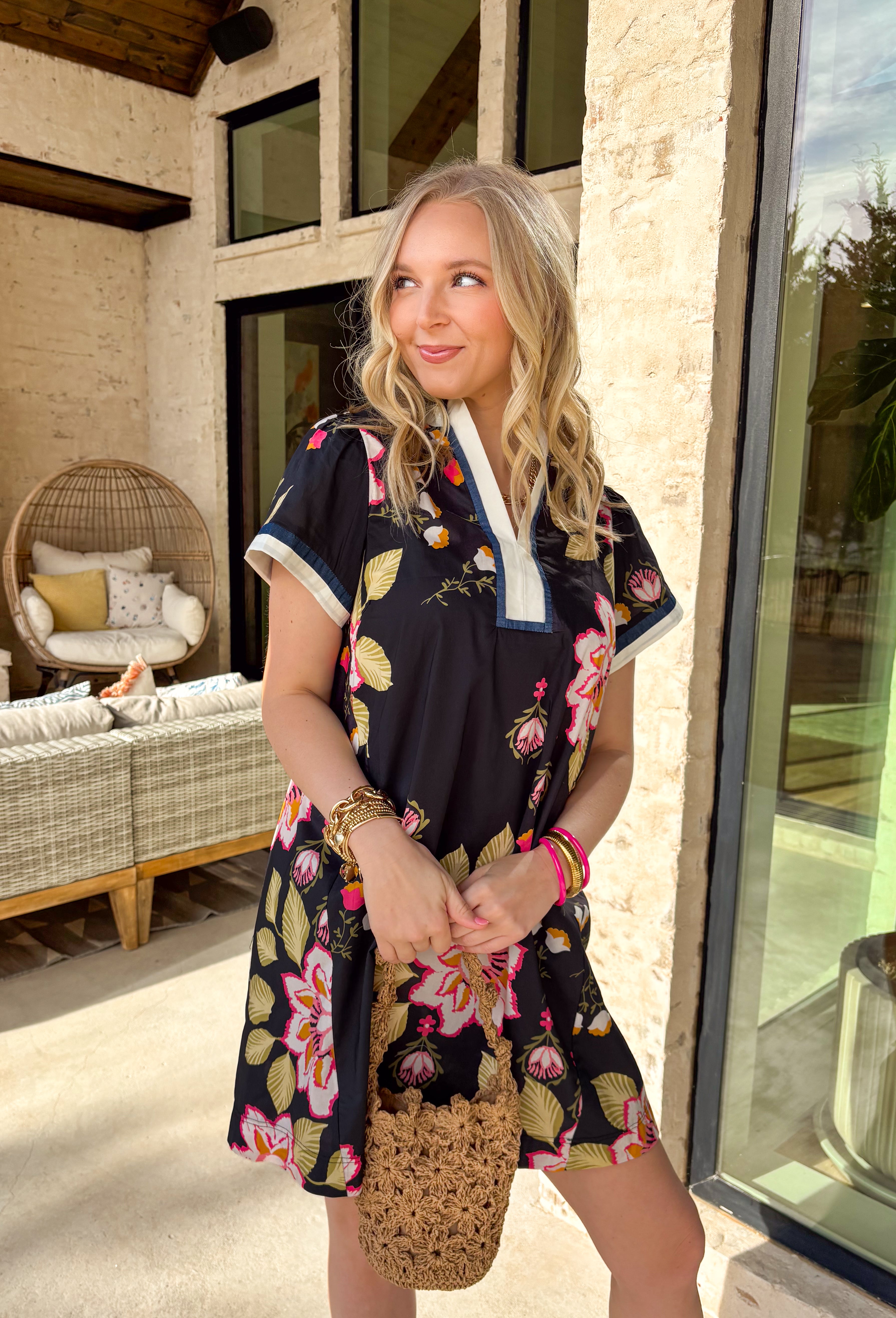 This black floral dress is the easiest way to bring a little spring color into your day! Covered in a cheerful mix of pink, green, white, and orange blooms, it’s bright, fun, and still super wearable thanks to the classic black background. The navy and white trim along the front and sleeve cuffs adds a sporty-chic touch, while the side pockets make it even more of a win