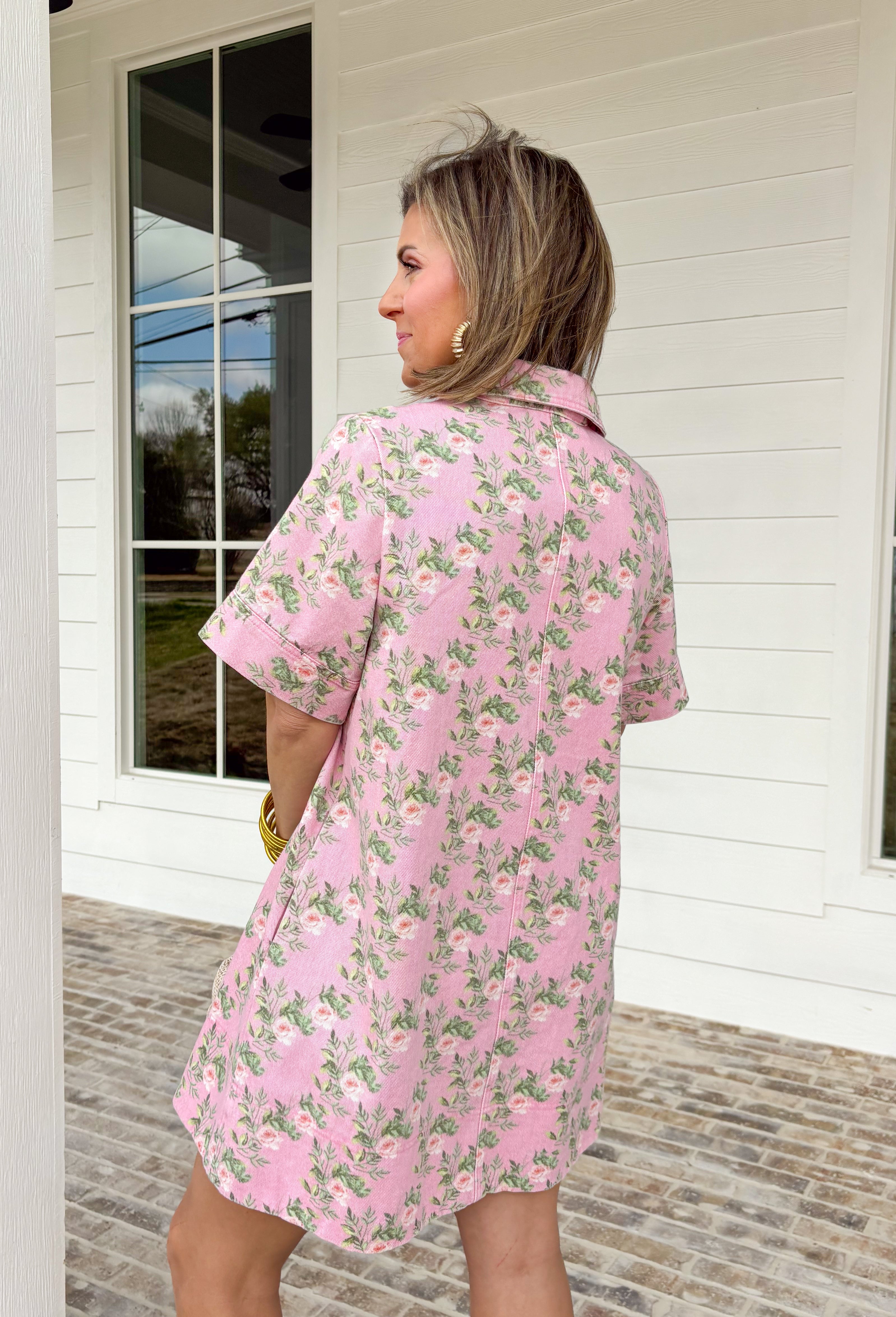 Soft denim meets spring florals in this light pink short sleeve dress by Entro. Featuring a pretty floral print throughout in shades of pink and green, this dress feels fresh, cheerful, and easy to wear. The collared neckline and front button details give it a classic, polished look, while front and side pockets keep it practical for everyday wear. Made from a comfortable stretch denim, this dress is perfect for spring days when you want something cute, comfortable, and effortlessly put together.