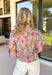Say hello to your new spring mood booster! This colorful floral top by Voy is bursting with happy shades of green, pink, blue, and red—aka the kind of print that makes you feel instantly more put-together (even if you’re just grabbing coffee). The navy and pink contrast trim down the front adds the cutest pop of detail, while the pink cuff sleeves with a sweet self-tie detail that give it a special finishing touch. 