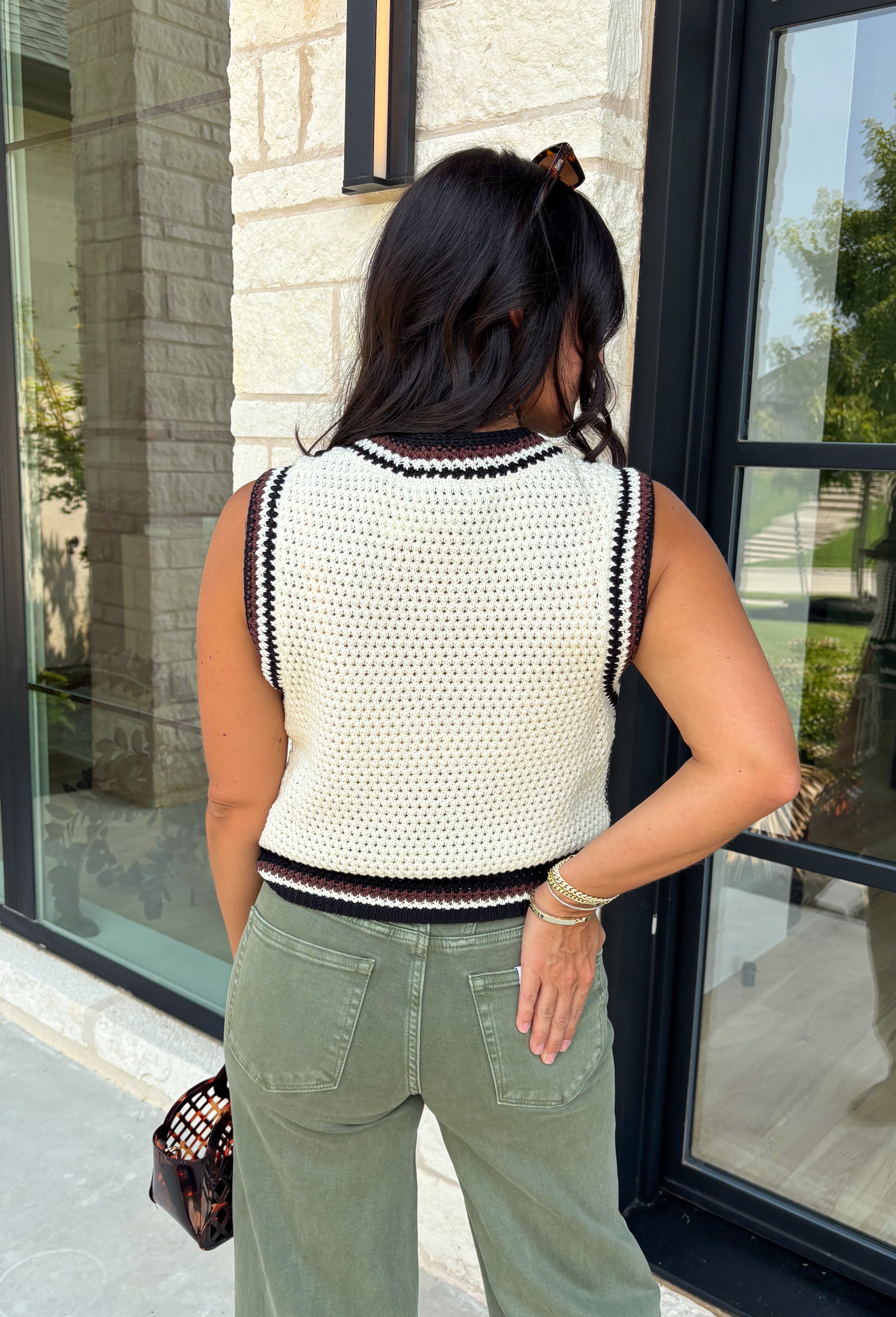 Elevate your everyday style with this timeless sweater knit that's equal parts classic and versatile. Crafted in an off-white knit with striking black and brown contrast trim, this sleeveless sweater offers a polished look you'll wear on repeat all season long. The button-front design makes it easy to style on its own or layered over a fitted long sleeve when temperatures start to cool. Whether you're heading to the office, brunch, or a weekend outing, this piece brings effortless charm to any outfit.