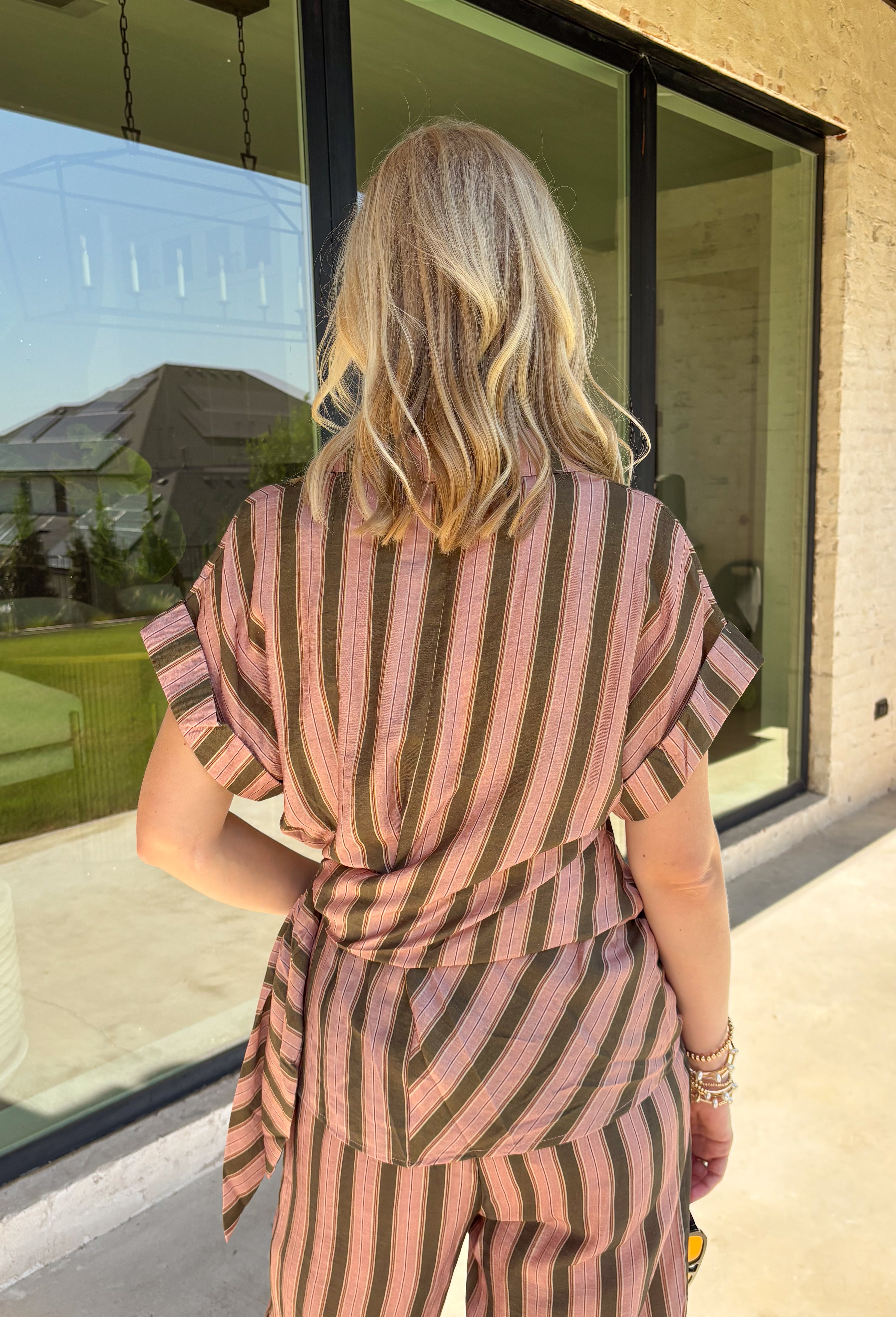 Warm neutral stripes make this Entro top an easy addition to your fall lineup. The button-front design gives it a classic feel, while the self-tie waist adds shape and a playful finishing touch. Short sleeves keep it lightweight enough for those warmer autumn days, making it an easy option for work, lunch plans, or a weekend out. Pair it with the matching pants for a coordinated two-piece set that does all the styling for you, or wear it individually with denim or solid bottoms for even more outfit options.