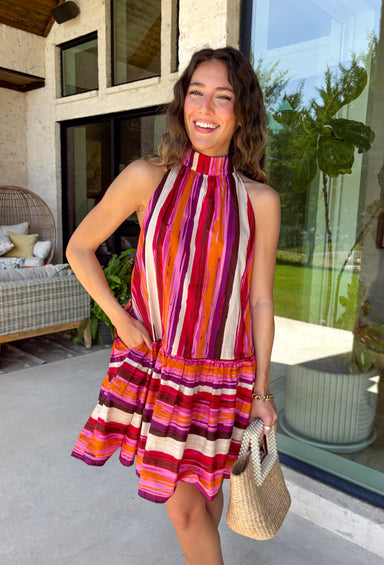 This striped dress is a beautiful way to welcome the new season! Featuring rich stripes in purple, pink, orange, and off white, it captures all the warmth and color of autumn while making a statement wherever you go. The self-tie bow at the back adds a feminine finishing touch, while the ruffle hem creates effortless movement with every step. Fully lined and finished with side pockets (always a favorite), this lightweight cotton dress is perfect.