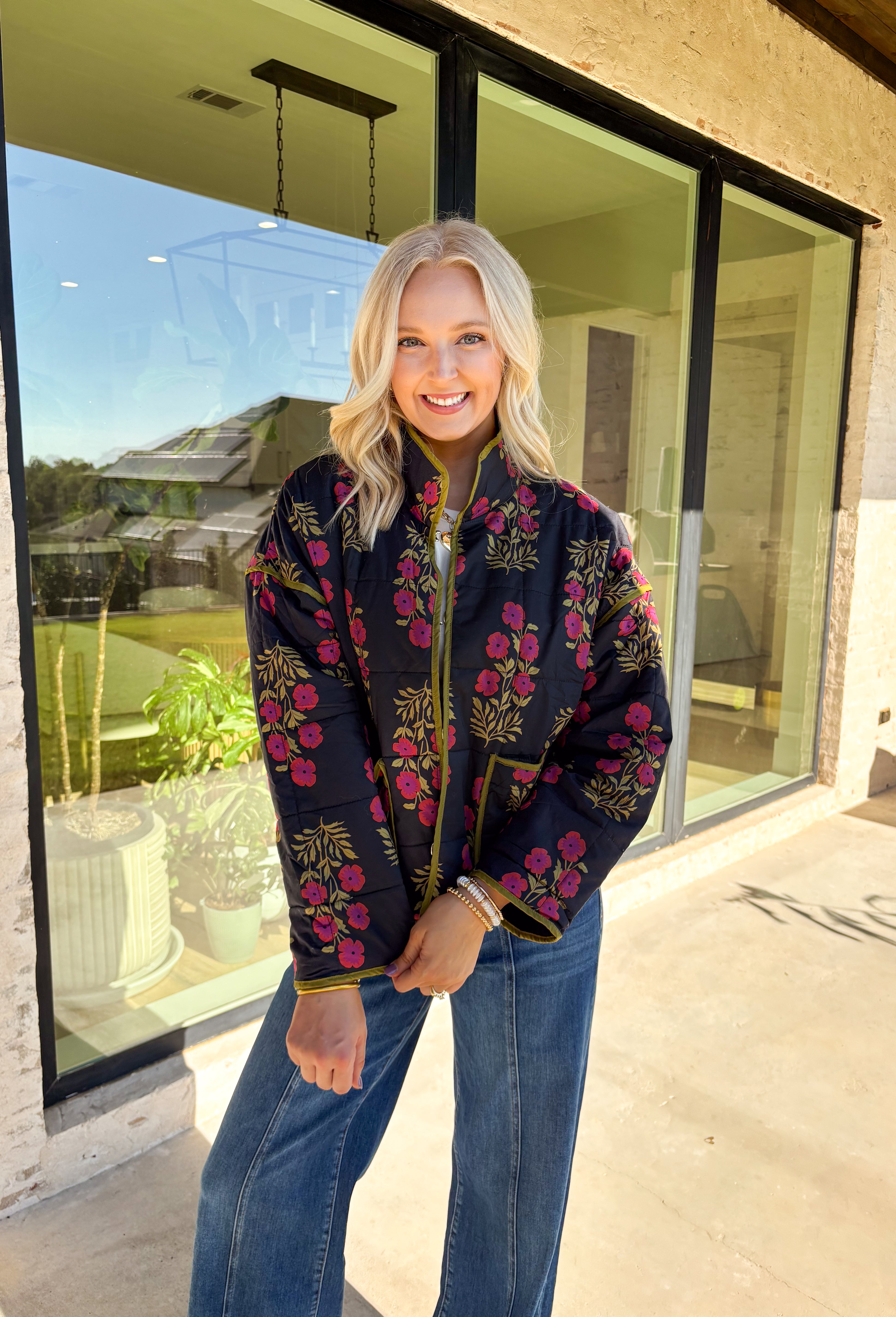 Wrap up in seasonal style with this black quilted jacket featuring a rich botanical print in olive and burgundy tones. Contrast binding highlights the edges for a polished finish, while front patch pockets add both function and charm. The hook-and-eye closure keeps the silhouette clean and simple, and the all-cotton design makes it cozy yet breathable for cool fall days. Whether layered over a sweater or paired with a casual tee, this jacket is a statement piece you’ll wear on repeat.