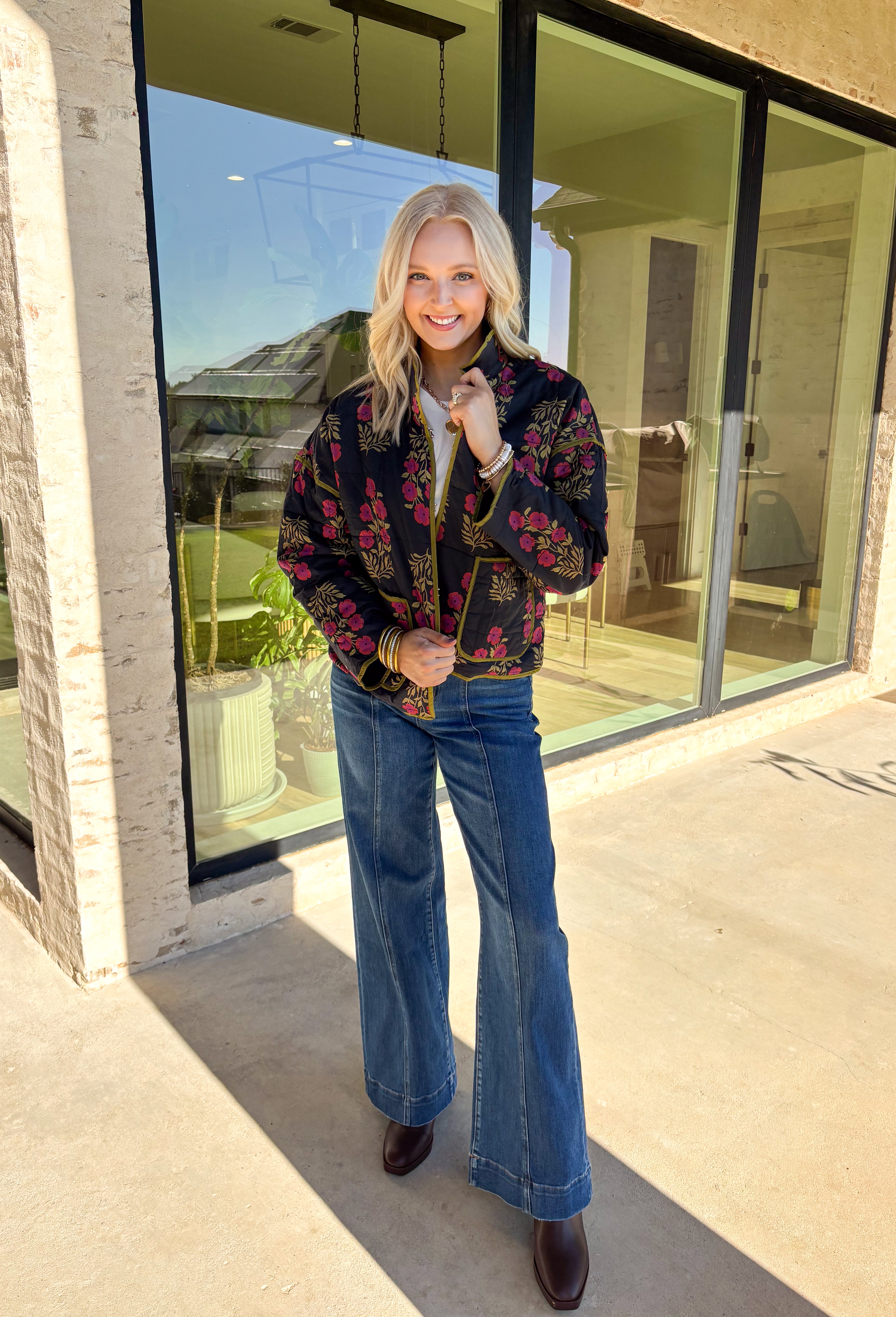 Wrap up in seasonal style with this black quilted jacket featuring a rich botanical print in olive and burgundy tones. Contrast binding highlights the edges for a polished finish, while front patch pockets add both function and charm. The hook-and-eye closure keeps the silhouette clean and simple, and the all-cotton design makes it cozy yet breathable for cool fall days. Whether layered over a sweater or paired with a casual tee, this jacket is a statement piece you’ll wear on repeat.