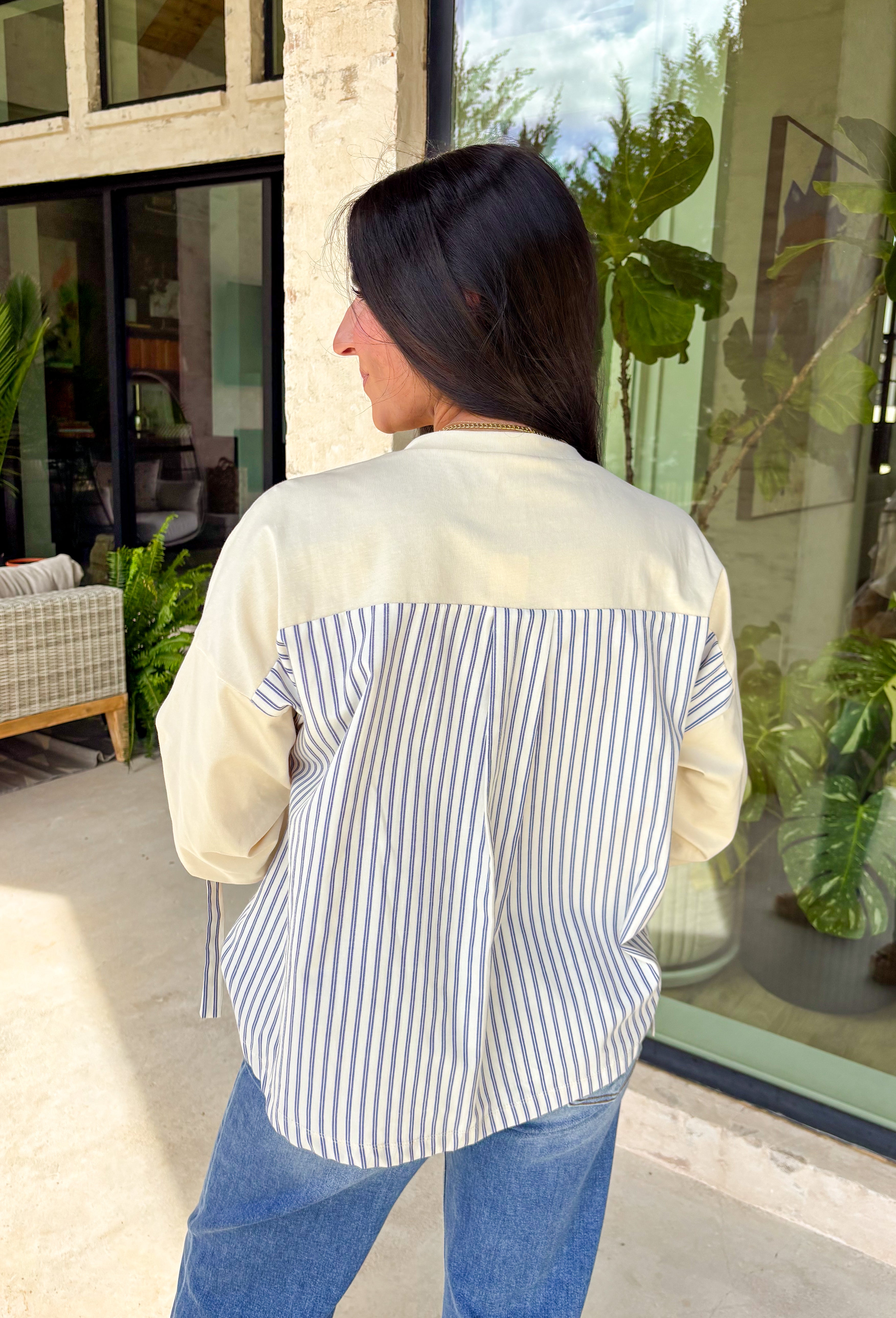Effortless style meets thoughtful detail in this neutral short sleeve top. The solid front keeps the look clean and classic, while the contrasting blue striped hem and back panel add a fresh pop of pattern that makes it feel a little extra special. Ruched drawstring detailing on the sleeves gives it a subtle, adjustable touch that adds texture and personality. Crafted from breathable cotton, this top is lightweight, comfortable, and perfect for everyday wear while still feeling polished.