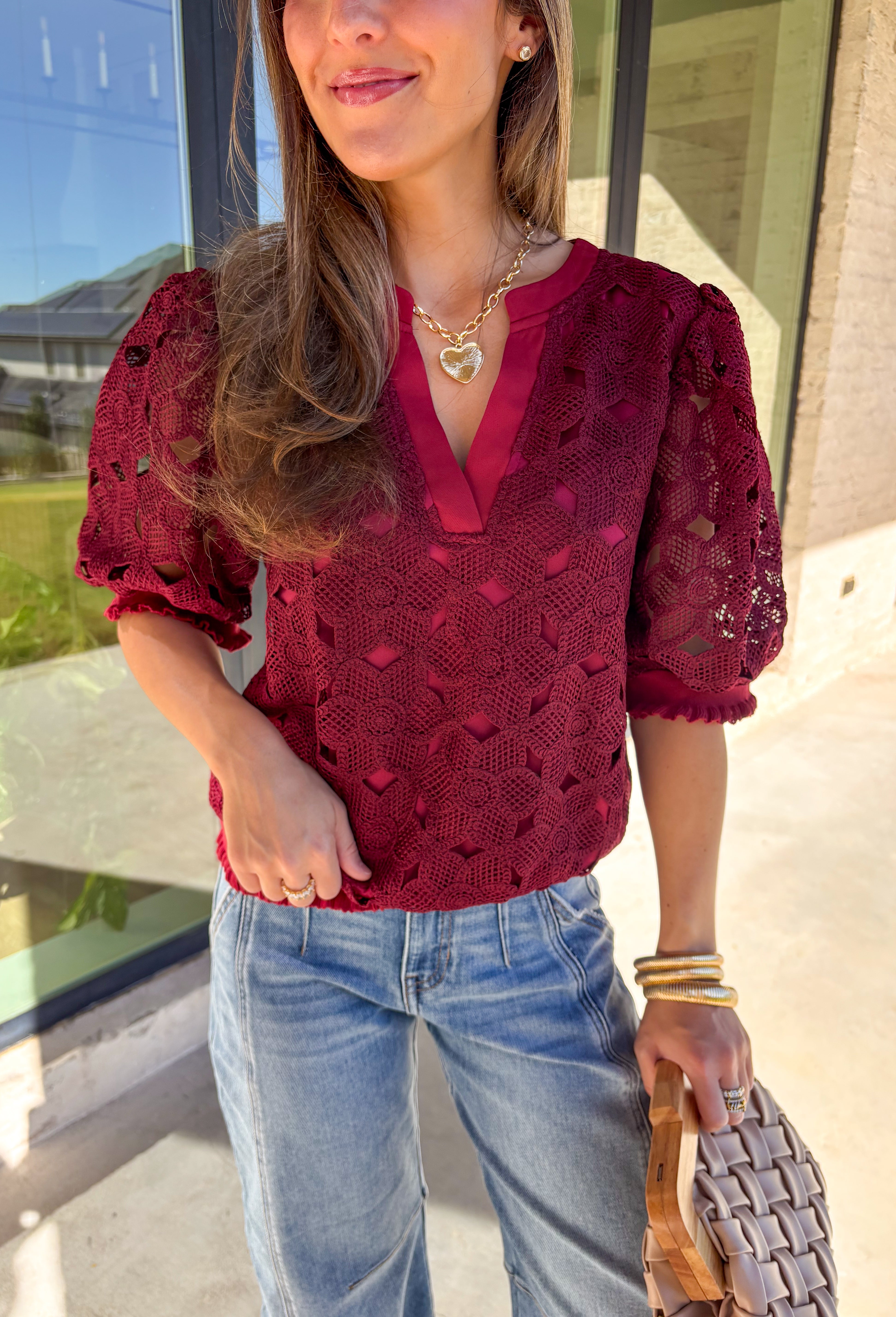 Romantic and feminine, this burgundy crochet lace overlay top by Voy is the perfect piece to elevate your fall wardrobe. The delicate lace design gives it beautiful texture, while the short sleeves and v-neckline add an effortless touch. Lettuce trim along the sleeves and hemline adds a soft, finished detail that keeps the look both classic and fresh.
