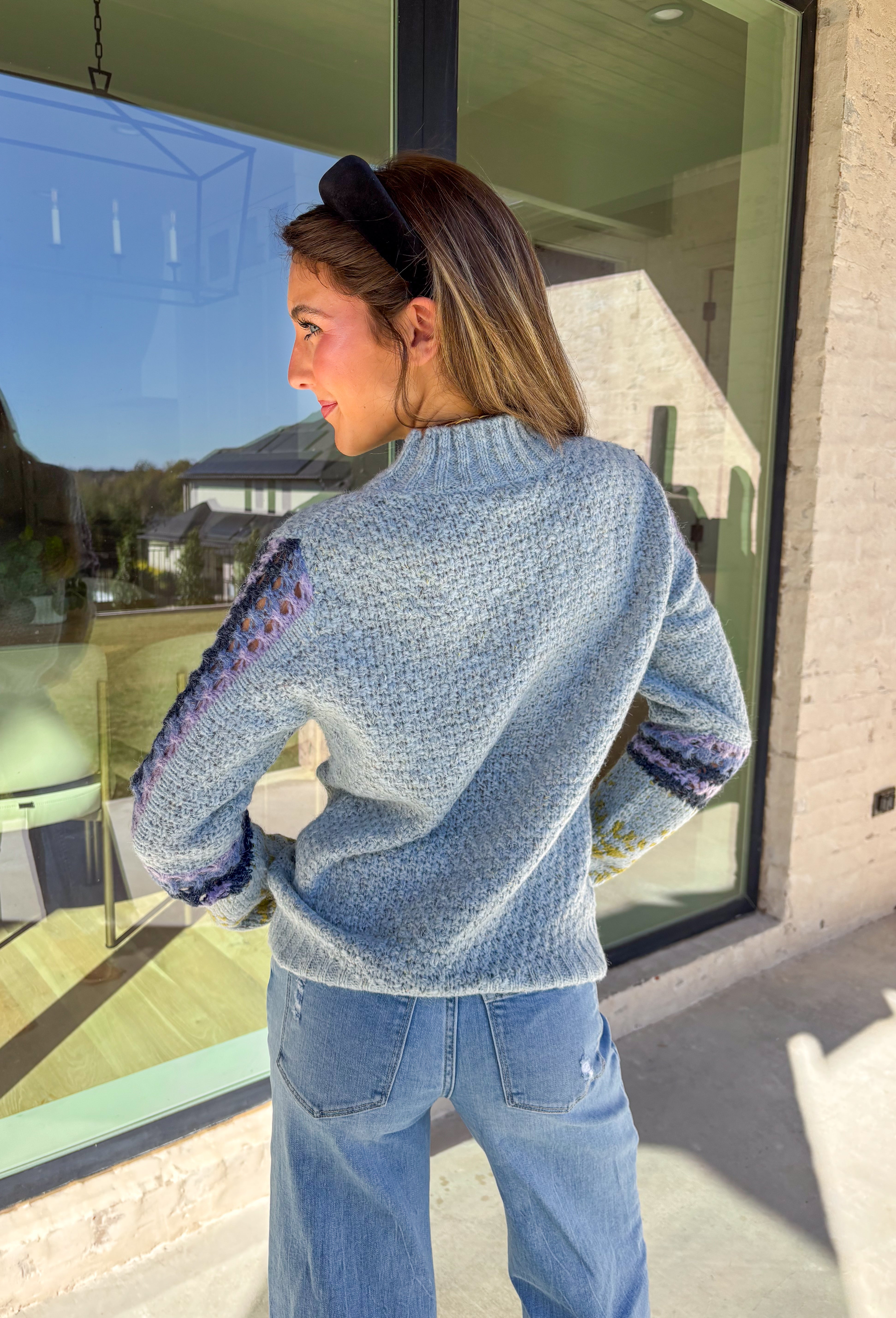 Bring a little color to chilly days with this cozy light blue knit sweater by Mystree. The mock neck design keeps you warm, while the abstract print sleeves—featuring shades of navy, light purple, and green—add a playful, modern twist. Soft, warm, and stylish, this sweater is an easy pick for staying cozy and cute all season long.