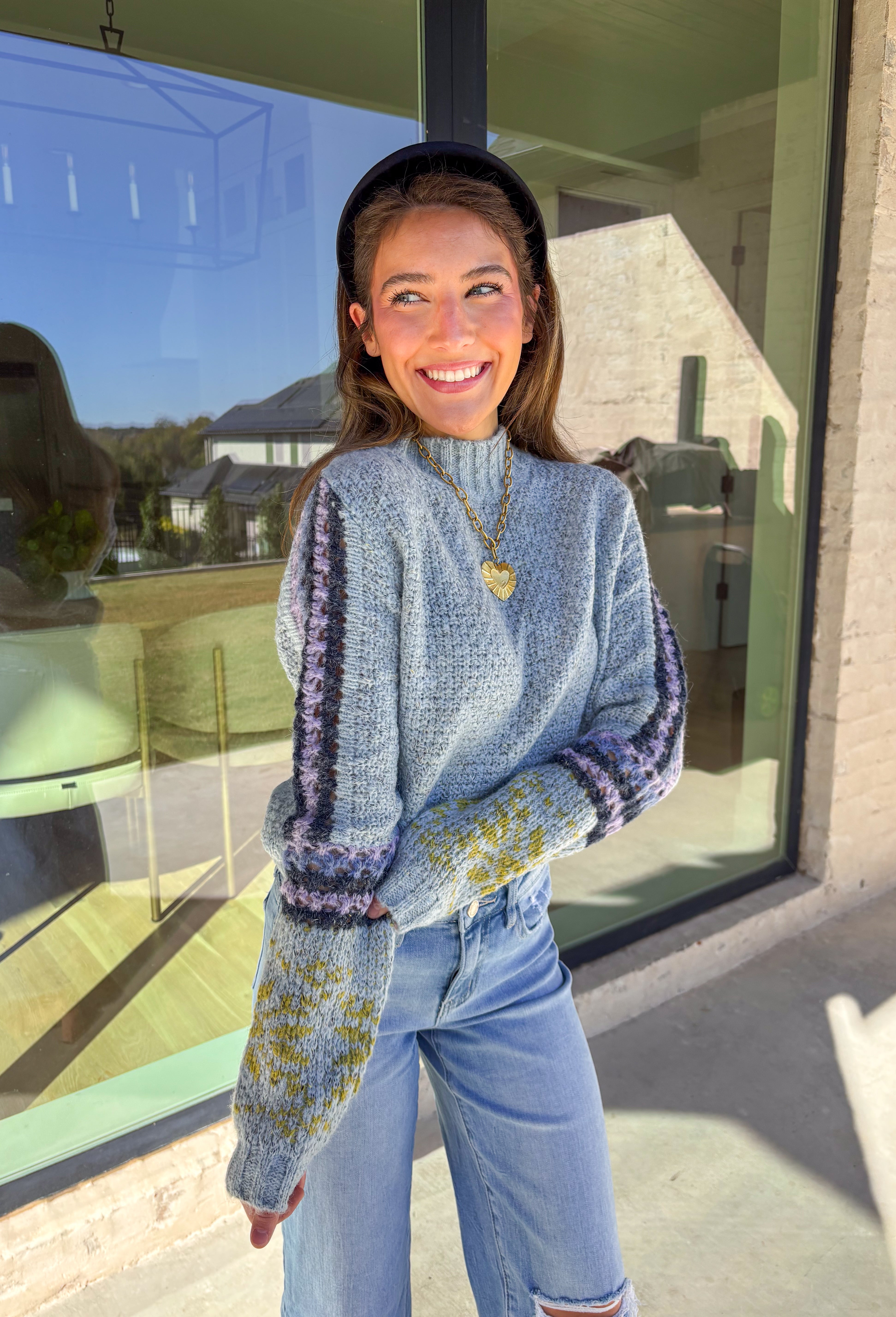 Bring a little color to chilly days with this cozy light blue knit sweater by Mystree. The mock neck design keeps you warm, while the abstract print sleeves—featuring shades of navy, light purple, and green—add a playful, modern twist. Soft, warm, and stylish, this sweater is an easy pick for staying cozy and cute all season long.