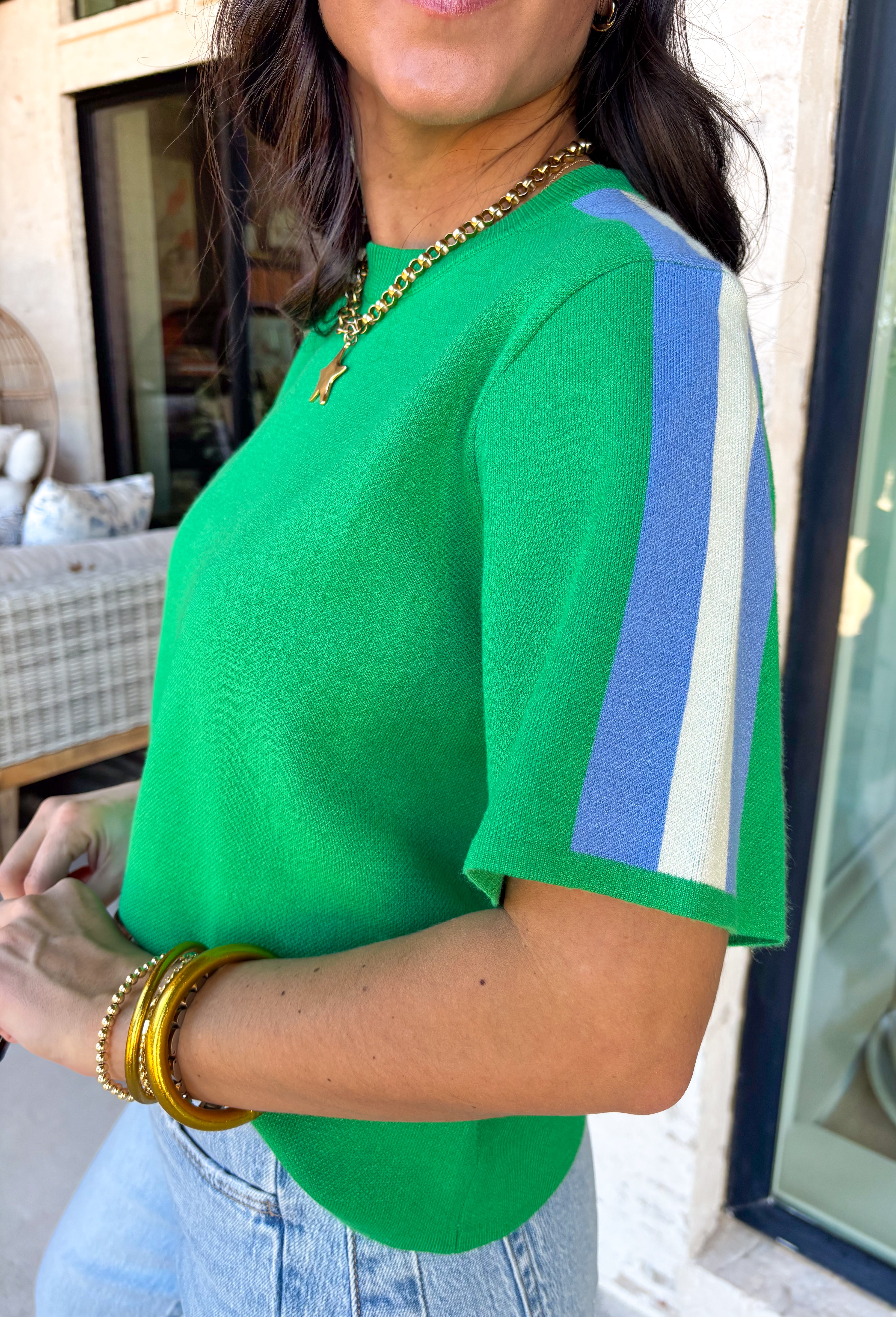 Sporty meets spring in this green short sleeve knit top by Entro. Designed with a soft, lightweight knit feel, it features a bold blue and white contrast stripe down the sides for a fun pop of color and a flattering, elongating look. Easy to dress up or down, this top is perfect for casual spring days when you still want something polished and comfortable.