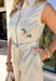 This neutral sleeveless jumpsuit is giving effortless spring charm with the prettiest embroidered details. Designed with colorful floral stitching in shades of blue, sage green, pink, and yellow, it features embroidery along the front and down the legs for a look that truly stands out. The ladder trim throughout adds subtle texture, while the lace scallop trim at the sleeves brings a soft, feminine finish. 