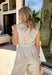 This neutral sleeveless jumpsuit is giving effortless spring charm with the prettiest embroidered details. Designed with colorful floral stitching in shades of blue, sage green, pink, and yellow, it features embroidery along the front and down the legs for a look that truly stands out. The ladder trim throughout adds subtle texture, while the lace scallop trim at the sleeves brings a soft, feminine finish. 