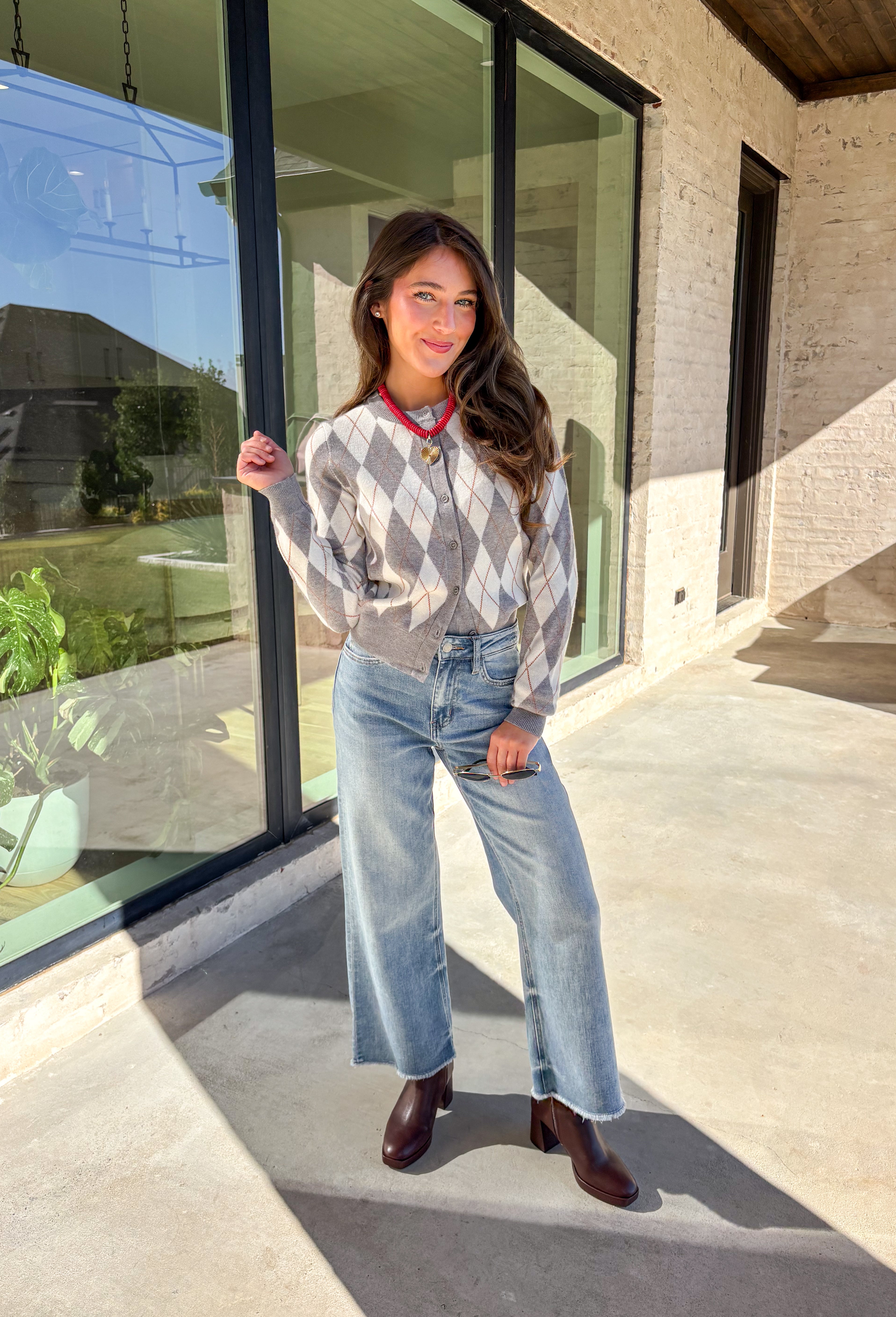 Classic pattern, cozy feel—this button-down cardigan by Haute Monde is the perfect layering piece for the season. Featuring a timeless gray and off-white argyle print with tan accents, it’s a modern twist on a preppy staple. The button-front design and soft knit fabric make it an easy go-to whether you’re dressing up for work or keeping it casual on weekends.