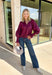 Bring a touch of romantic charm to your fall wardrobe with this beautifully detailed blouse from Entro. Designed in a rich burgundy hue, this feminine top features a softly smocked neckline with a delicate front tie for an effortlessly graceful look. The long sleeves are finished with smocked cuffs and lace trim, while the lace hem adds an elegant finishing touch. 