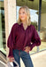 Bring a touch of romantic charm to your fall wardrobe with this beautifully detailed blouse from Entro. Designed in a rich burgundy hue, this feminine top features a softly smocked neckline with a delicate front tie for an effortlessly graceful look. The long sleeves are finished with smocked cuffs and lace trim, while the lace hem adds an elegant finishing touch. 