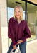 Bring a touch of romantic charm to your fall wardrobe with this beautifully detailed blouse from Entro. Designed in a rich burgundy hue, this feminine top features a softly smocked neckline with a delicate front tie for an effortlessly graceful look. The long sleeves are finished with smocked cuffs and lace trim, while the lace hem adds an elegant finishing touch. 