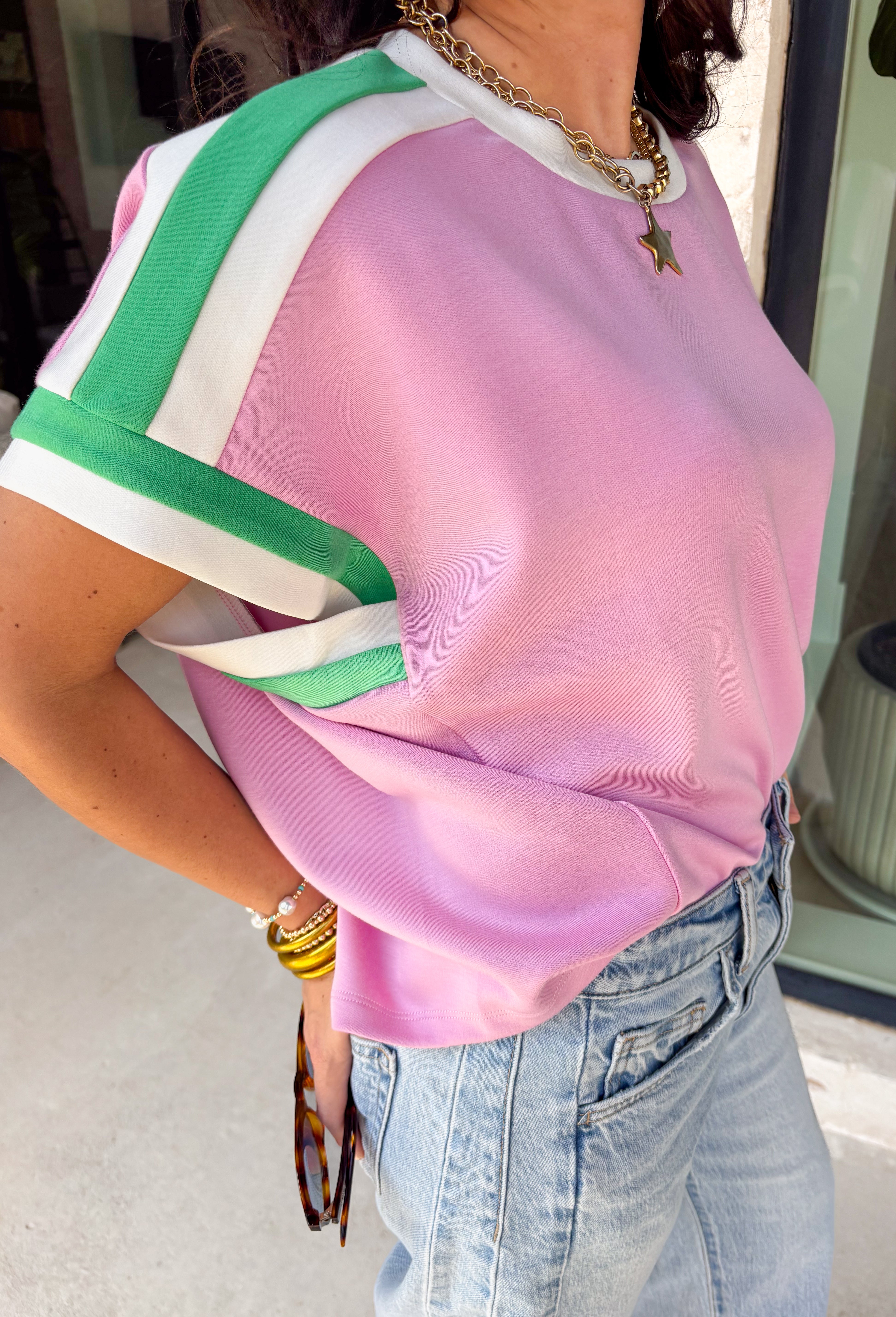 Cute, comfy, and just the right amount of sporty, this pink short sleeve knit top by Entro is such a fun spring staple. The green and white contrast trim along the neckline, sleeves, and shoulders gives it that fresh pop of color that makes even your simplest outfit feel styled. It’s lightweight with a soft, stretchy feel, making it perfect for busy days when you want to look put-together but stay comfortable. Pair it with denim shorts, white jeans, or even a casual skirt.