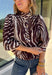 Neutral gets a little wild with this brown and cream zebra print blouse from Entro. The warm color combination makes the statement print easy to style while fitting perfectly into the transition from fall into winter. A stand collar and partial button-front closure give the lightweight silhouette a classic touch, while gathered detailing at the shoulders and back adds shape and movement.