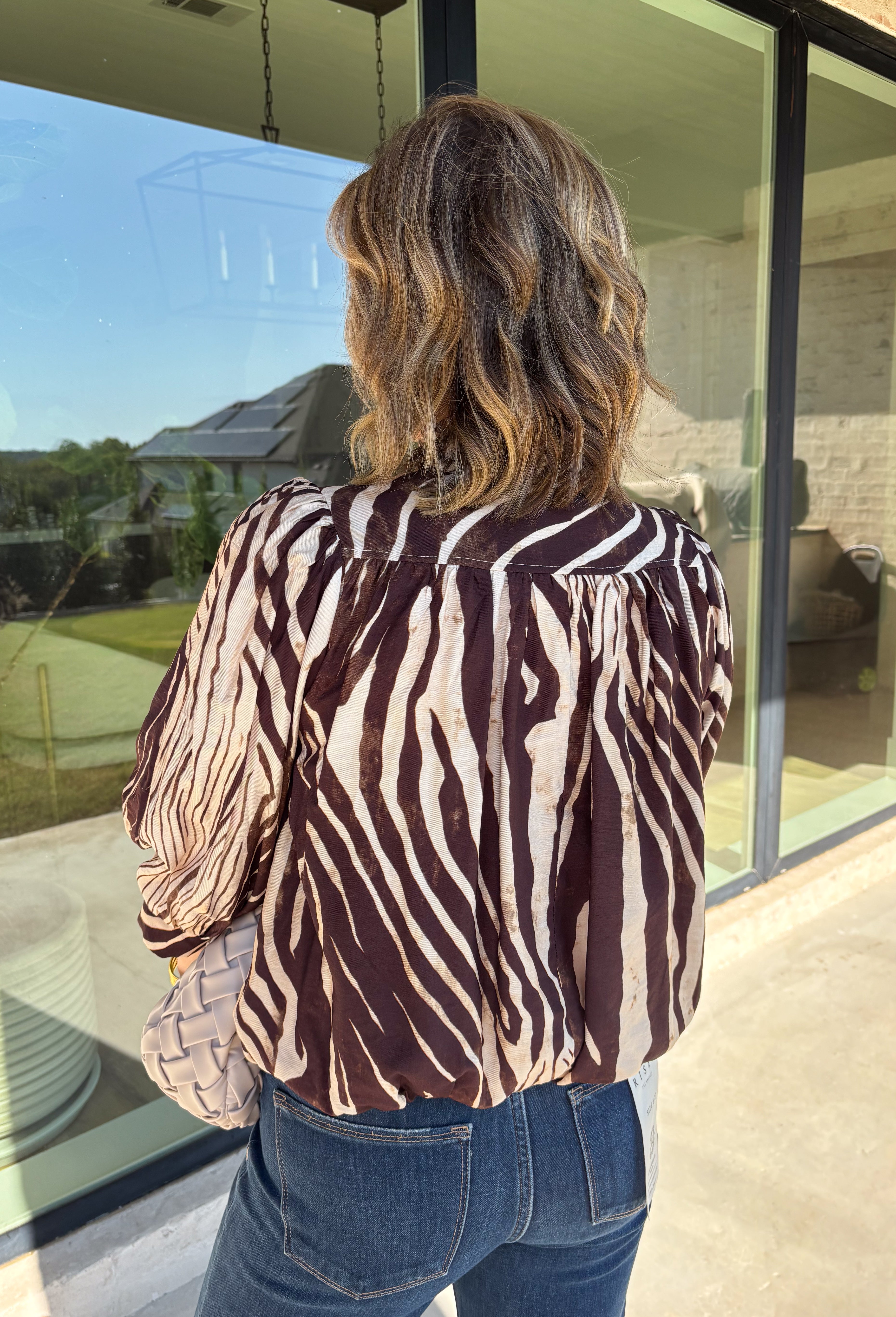 Neutral gets a little wild with this brown and cream zebra print blouse from Entro. The warm color combination makes the statement print easy to style while fitting perfectly into the transition from fall into winter. A stand collar and partial button-front closure give the lightweight silhouette a classic touch, while gathered detailing at the shoulders and back adds shape and movement.