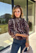 Neutral gets a little wild with this brown and cream zebra print blouse from Entro. The warm color combination makes the statement print easy to style while fitting perfectly into the transition from fall into winter. A stand collar and partial button-front closure give the lightweight silhouette a classic touch, while gathered detailing at the shoulders and back adds shape and movement.