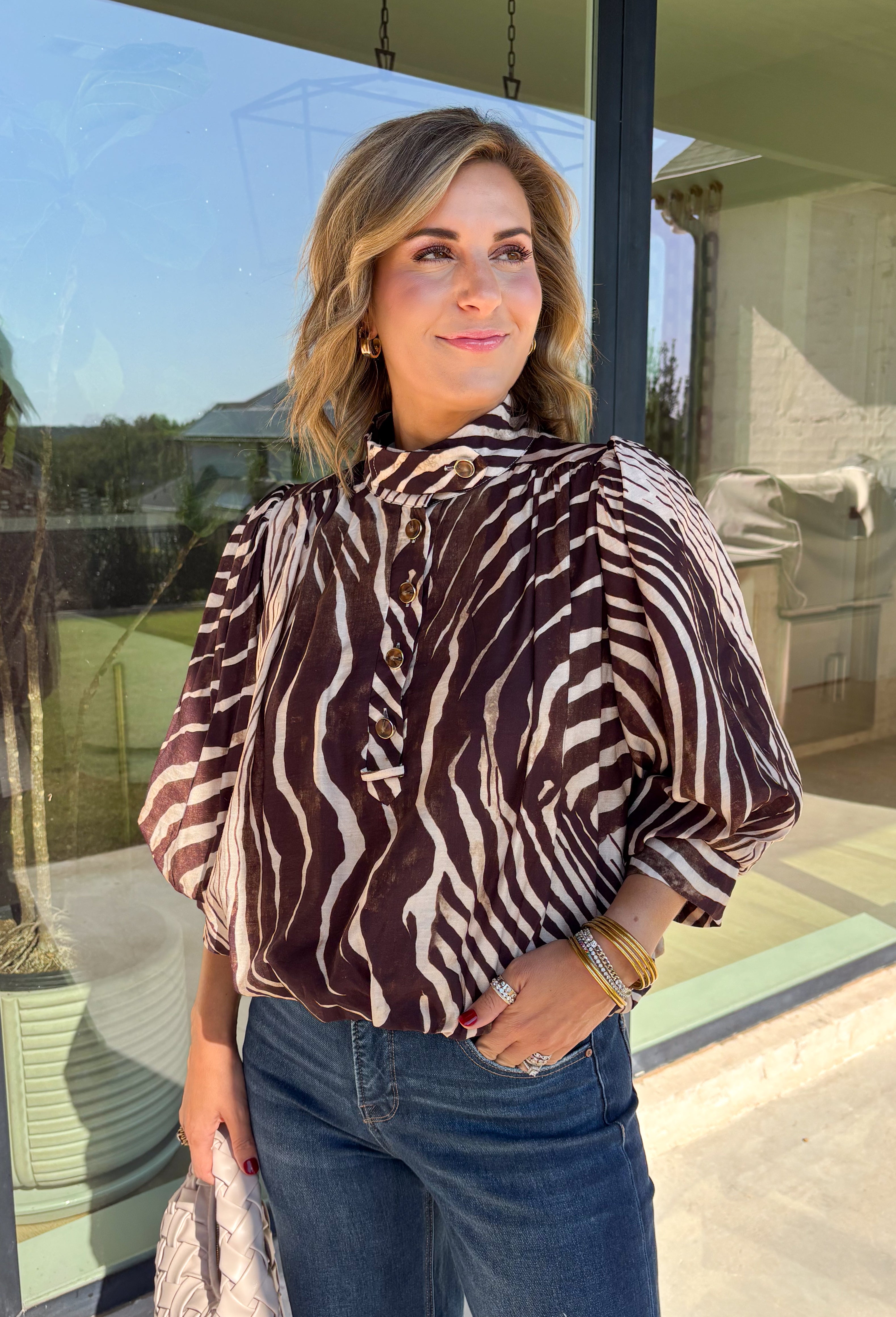Neutral gets a little wild with this brown and cream zebra print blouse from Entro. The warm color combination makes the statement print easy to style while fitting perfectly into the transition from fall into winter. A stand collar and partial button-front closure give the lightweight silhouette a classic touch, while gathered detailing at the shoulders and back adds shape and movement.