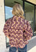 Soft, feminine, and full of seasonal charm, this floral blouse is an effortless addition to your fall wardrobe. Designed with a beautiful blush backdrop and a rich burgundy and tan floral print, this top brings together warm autumn hues in a timeless silhouette. The button-front design adds classic appeal, while the ruffle hem creates a flattering, feminine finish. Gathered detailing at the back yoke gives this blouse a relaxed, flowy fit that's perfect for everything from workdays to weekend outings.