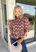 Soft, feminine, and full of seasonal charm, this floral blouse is an effortless addition to your fall wardrobe. Designed with a beautiful blush backdrop and a rich burgundy and tan floral print, this top brings together warm autumn hues in a timeless silhouette. The button-front design adds classic appeal, while the ruffle hem creates a flattering, feminine finish. Gathered detailing at the back yoke gives this blouse a relaxed, flowy fit that's perfect for everything from workdays to weekend outings.