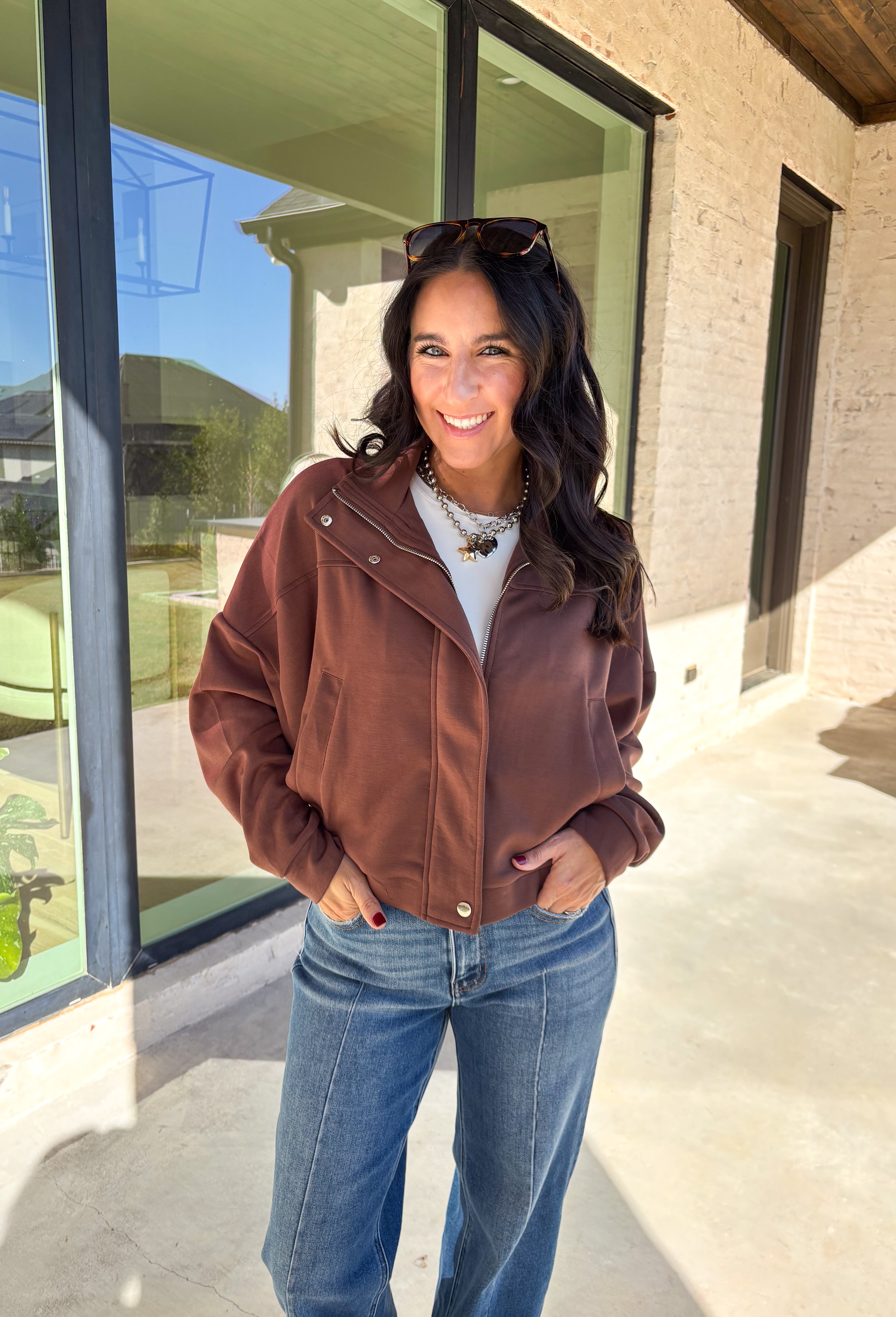 Add a touch of effortless cool to your winter wardrobe with this chocolate brown bomber jacket by Iris. Designed with a cropped silhouette and soft dolman sleeves, it’s a modern twist on a classic favorite. The snap collar, front pockets, and zip closure give it that timeless bomber edge, while the cozy fabric blend keeps it soft and easy to wear all season long.