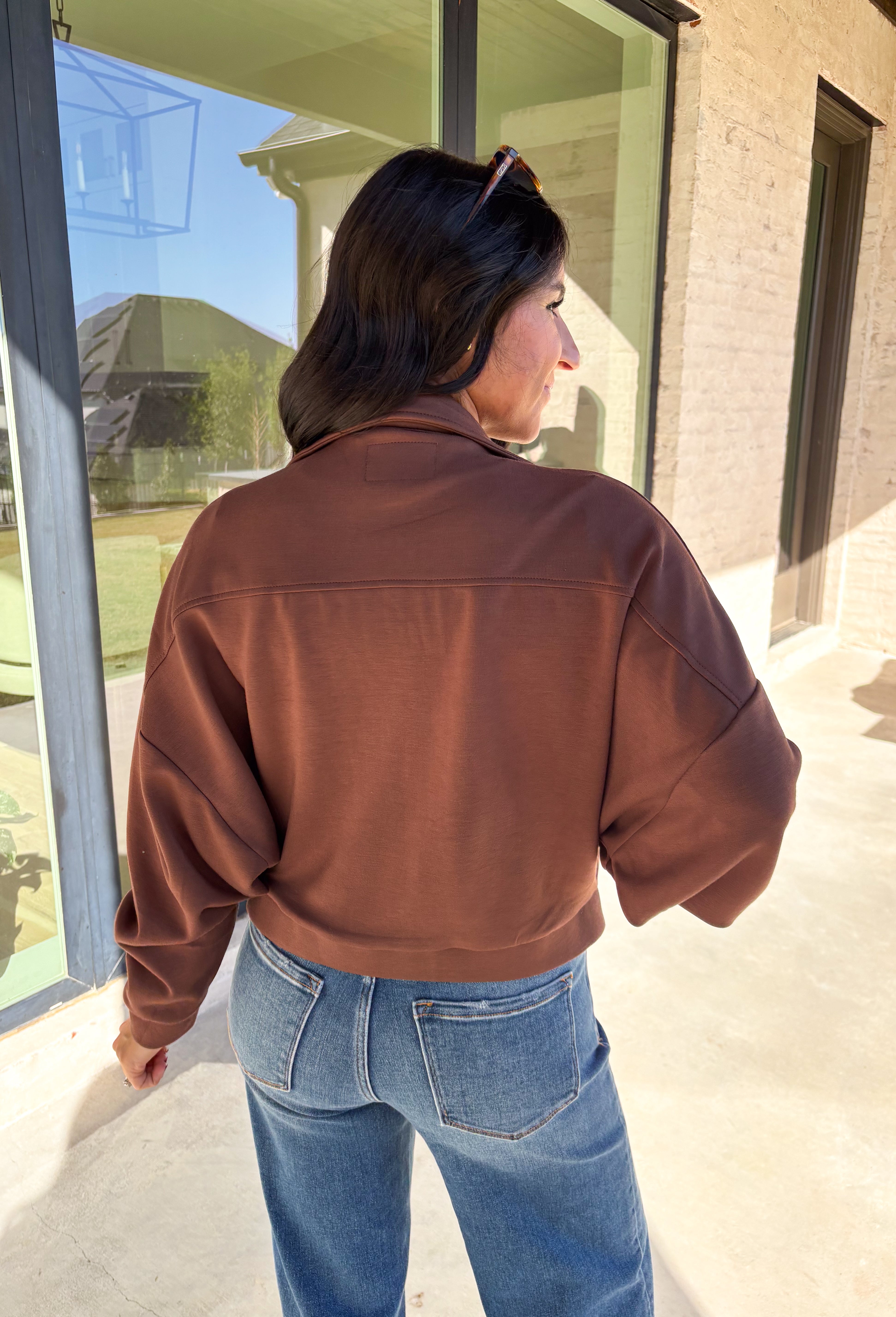 Add a touch of effortless cool to your winter wardrobe with this chocolate brown bomber jacket by Iris. Designed with a cropped silhouette and soft dolman sleeves, it’s a modern twist on a classic favorite. The snap collar, front pockets, and zip closure give it that timeless bomber edge, while the cozy fabric blend keeps it soft and easy to wear all season long.