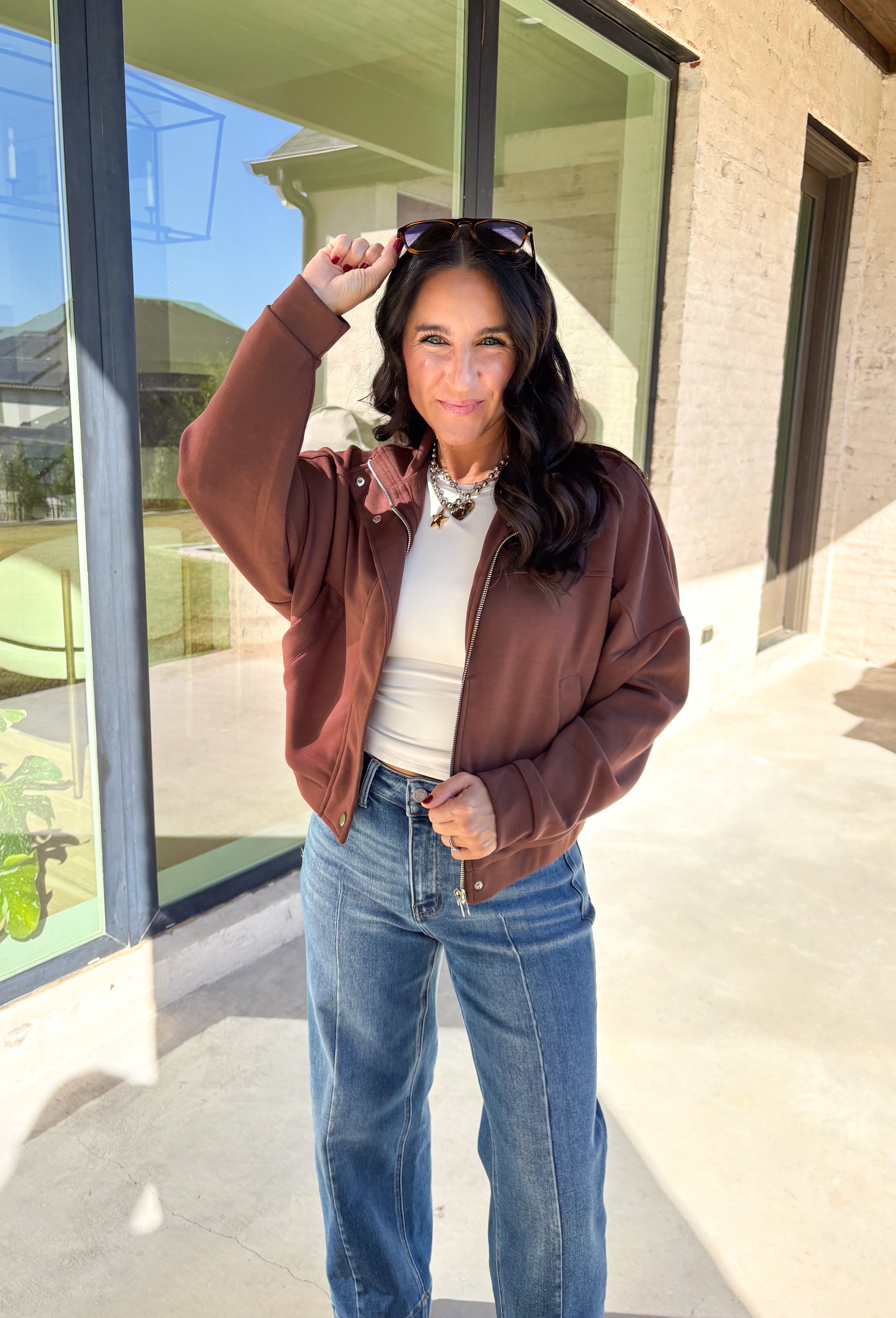 Add a touch of effortless cool to your winter wardrobe with this chocolate brown bomber jacket by Iris. Designed with a cropped silhouette and soft dolman sleeves, it’s a modern twist on a classic favorite. The snap collar, front pockets, and zip closure give it that timeless bomber edge, while the cozy fabric blend keeps it soft and easy to wear all season long.