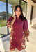 This burgundy button-down dress by Entro is a timeless piece with a fall-ready twist. Featuring a delicate floral print along the sides, it’s designed with a ruffled accent v-neckline for a touch of femininity. The elastic sleeves make for an easy, comfortable fit, while the full lining ensures effortless wear. With its rich color and flattering silhouette, this dress transitions seamlessly from day to night.