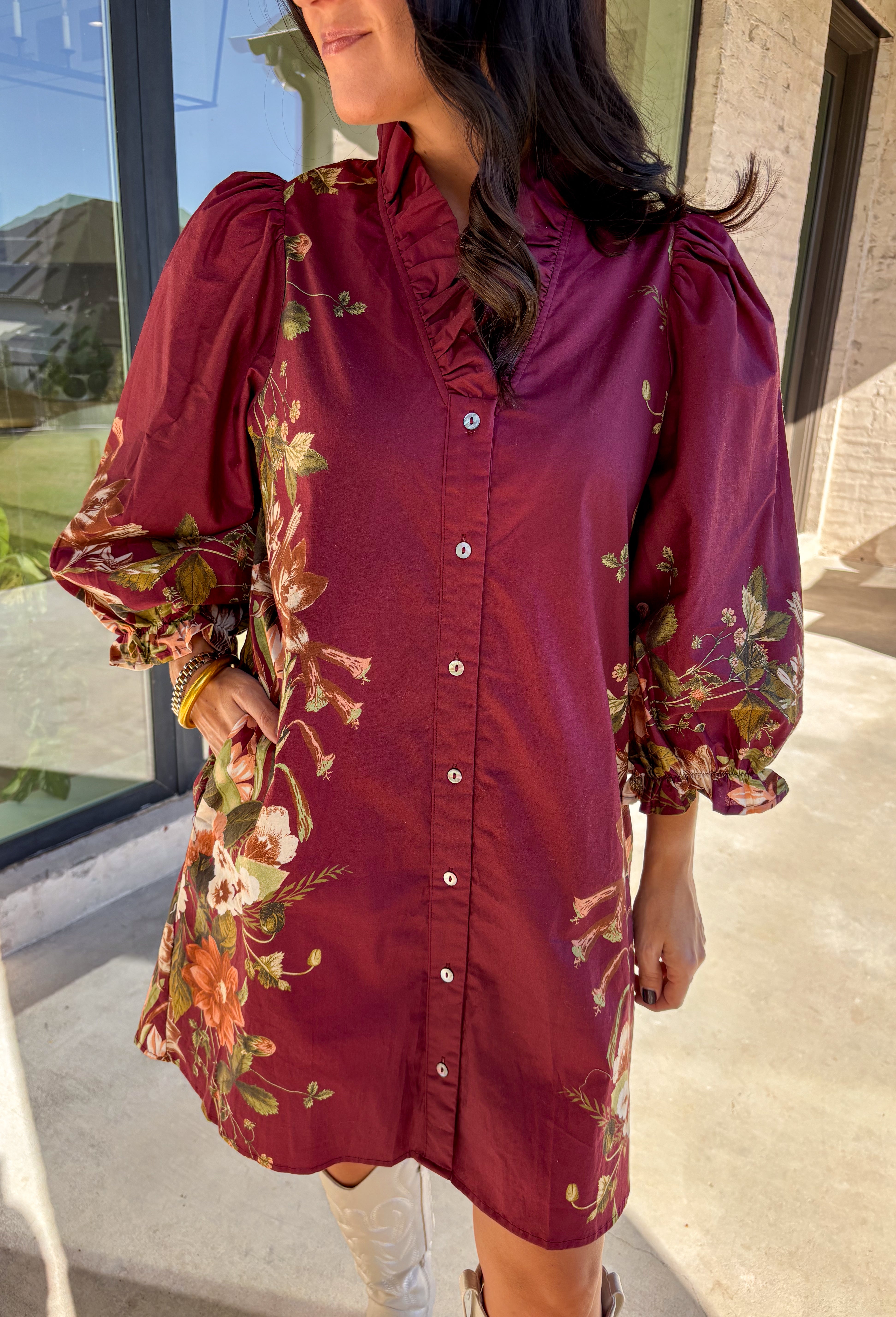 This burgundy button-down dress by Entro is a timeless piece with a fall-ready twist. Featuring a delicate floral print along the sides, it’s designed with a ruffled accent v-neckline for a touch of femininity. The elastic sleeves make for an easy, comfortable fit, while the full lining ensures effortless wear. With its rich color and flattering silhouette, this dress transitions seamlessly from day to night.